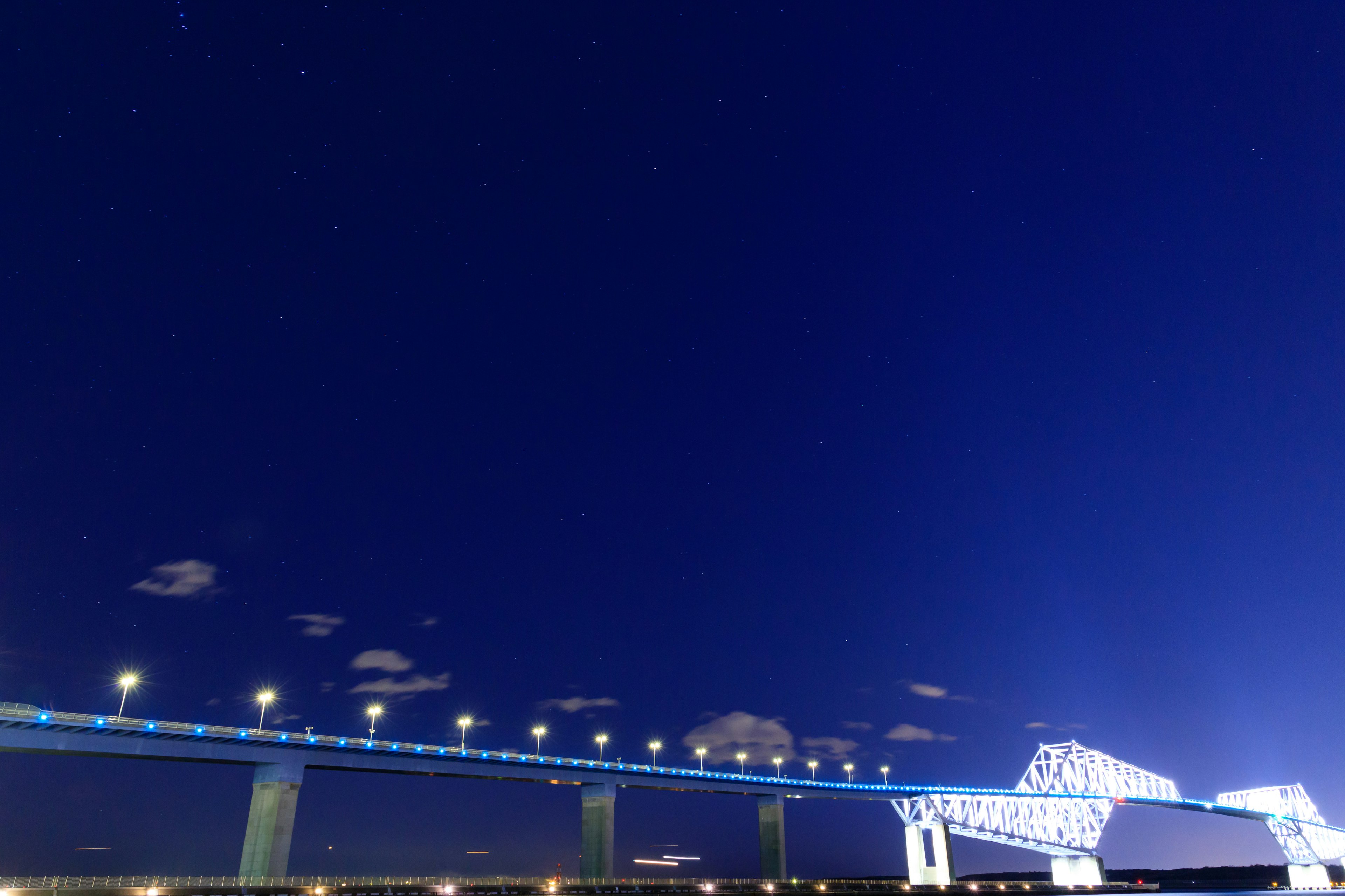 Siluet jembatan yang diterangi di bawah langit malam biru yang dalam