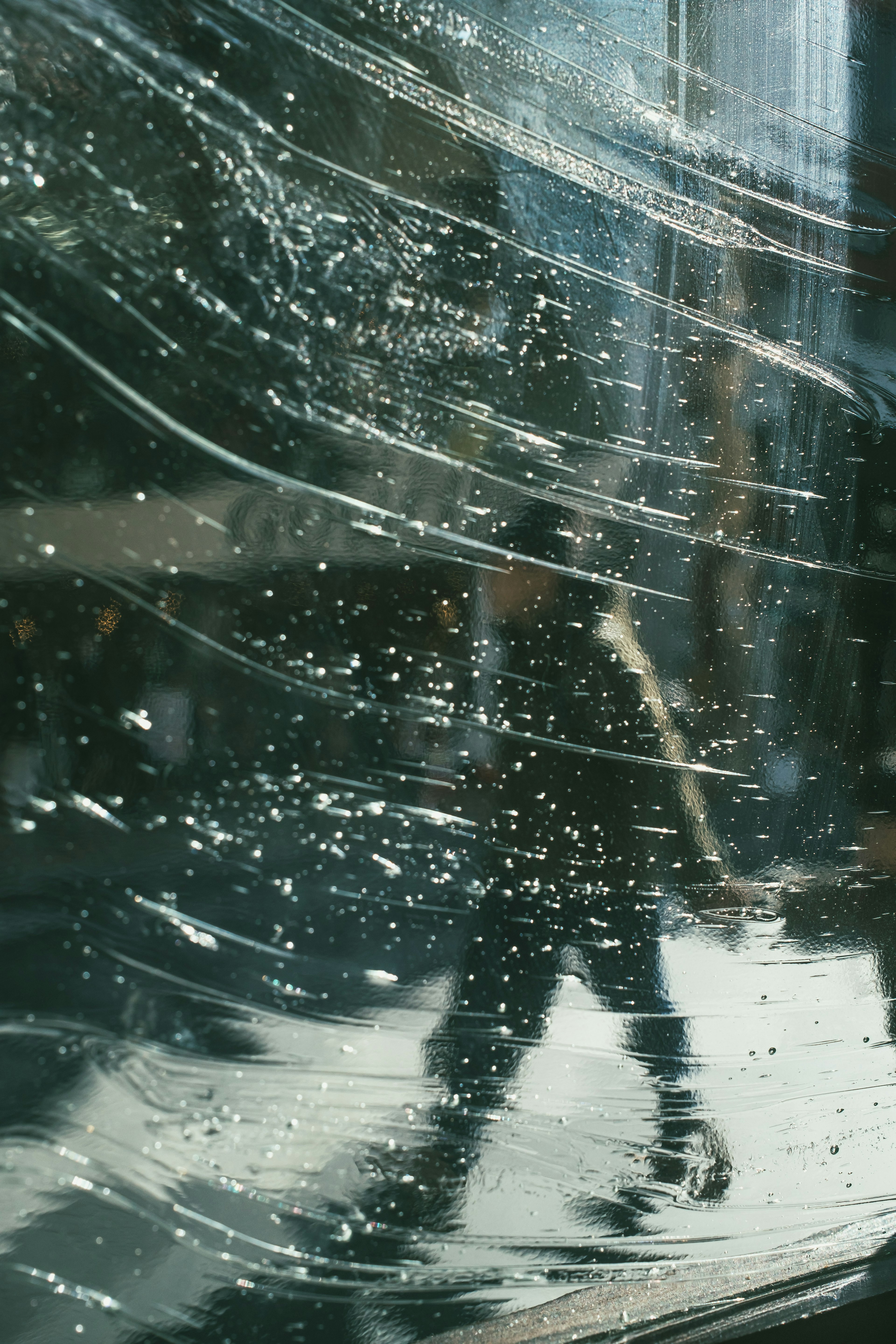 Silhouette of a person walking through a glass with water droplets