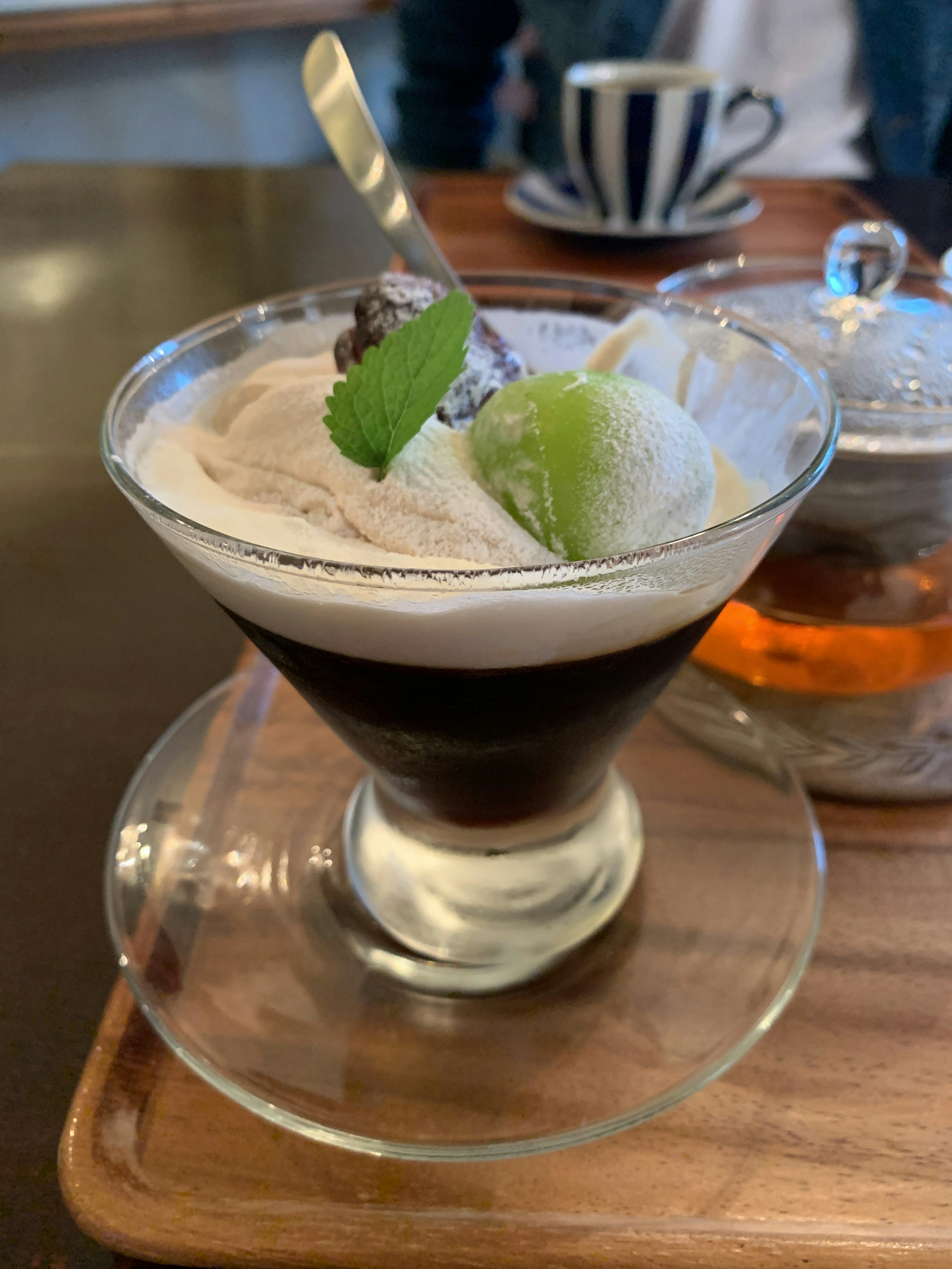 Verre à dessert avec café noir surmonté de crème glacée garni de feuilles de menthe et de glace verte