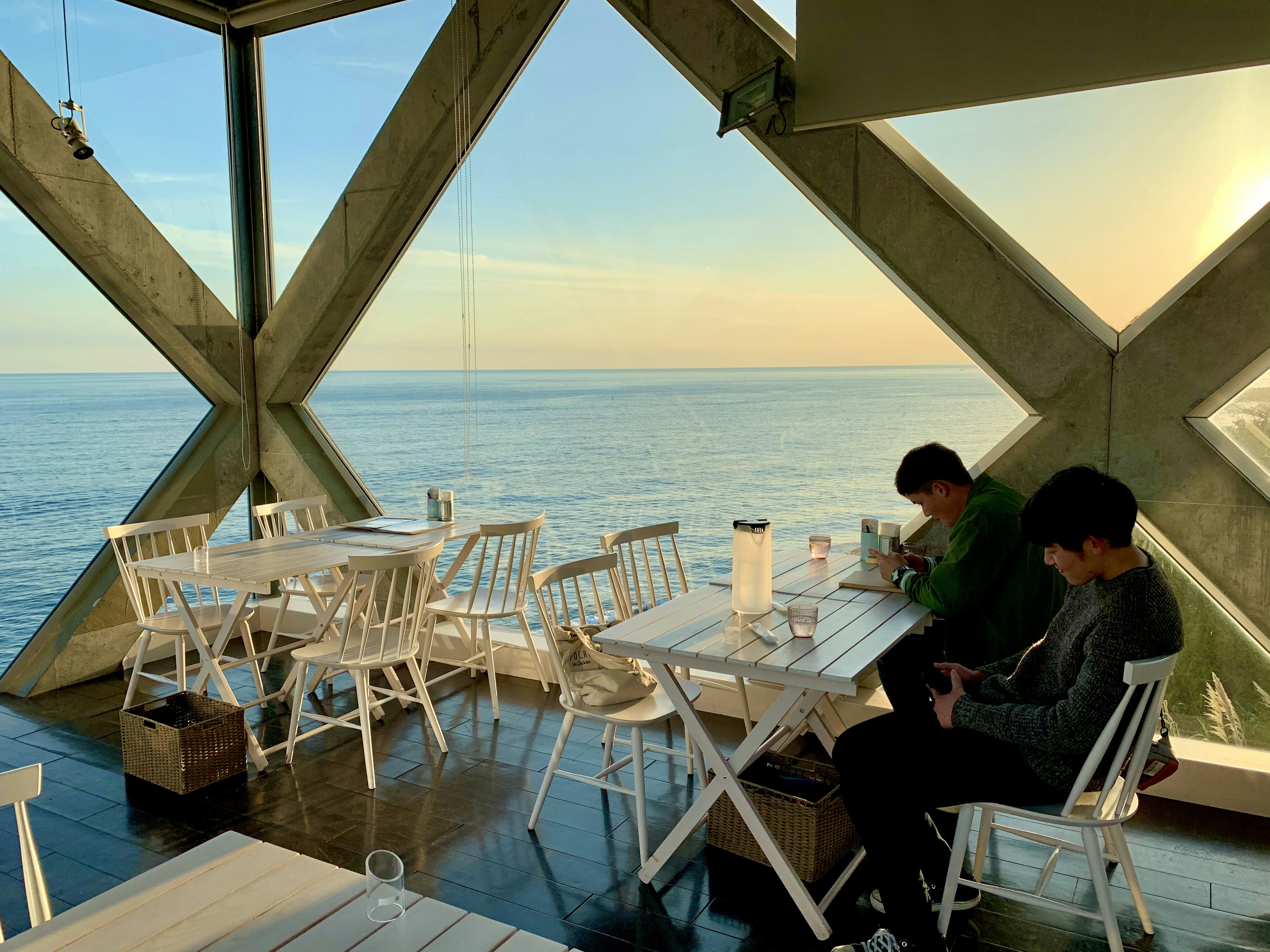 Interior de un café moderno con vista al mar dos clientes sentados en silencio