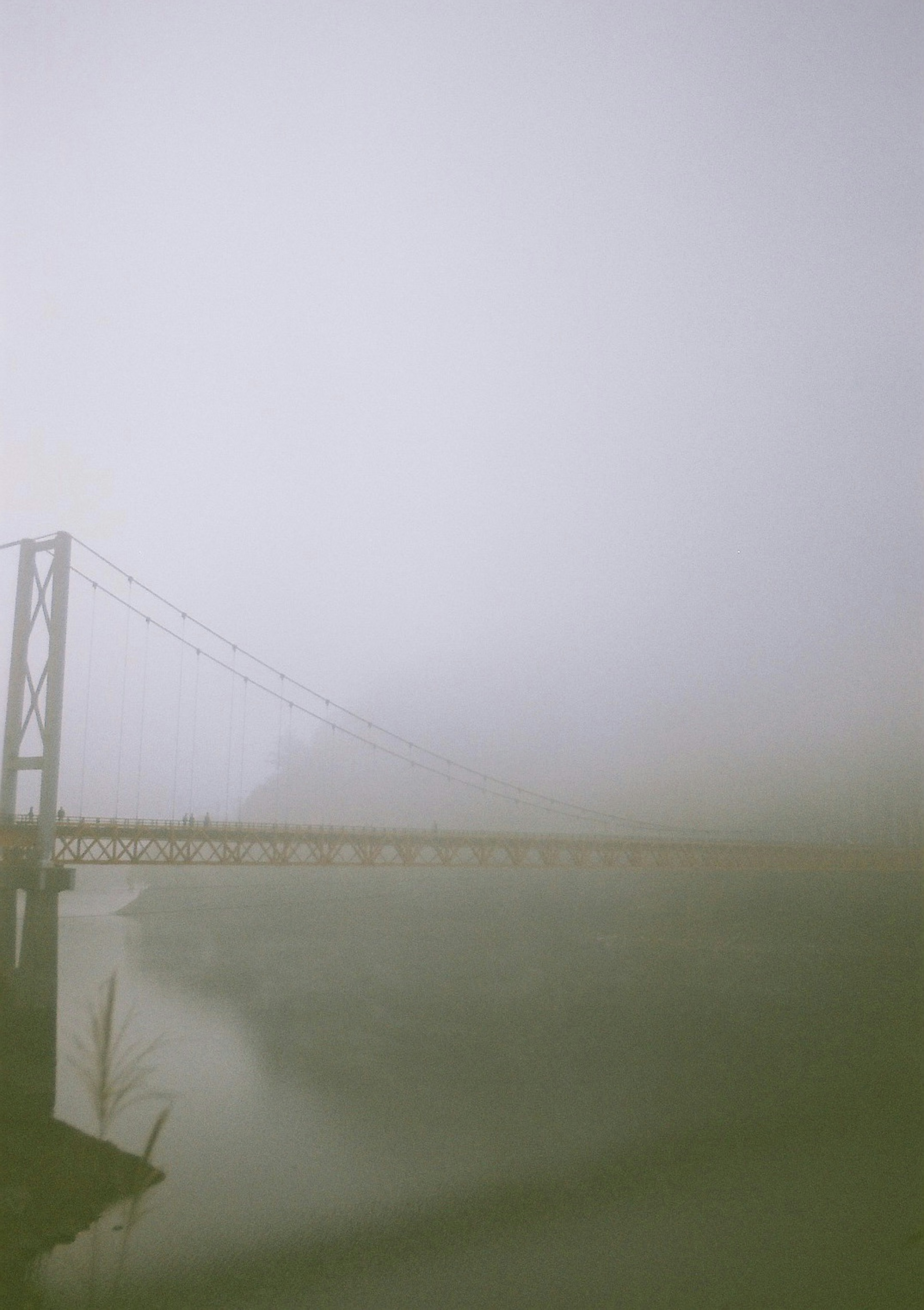 Eine im Nebel gehüllte Hängebrücke mit einer ruhigen Wasseroberfläche