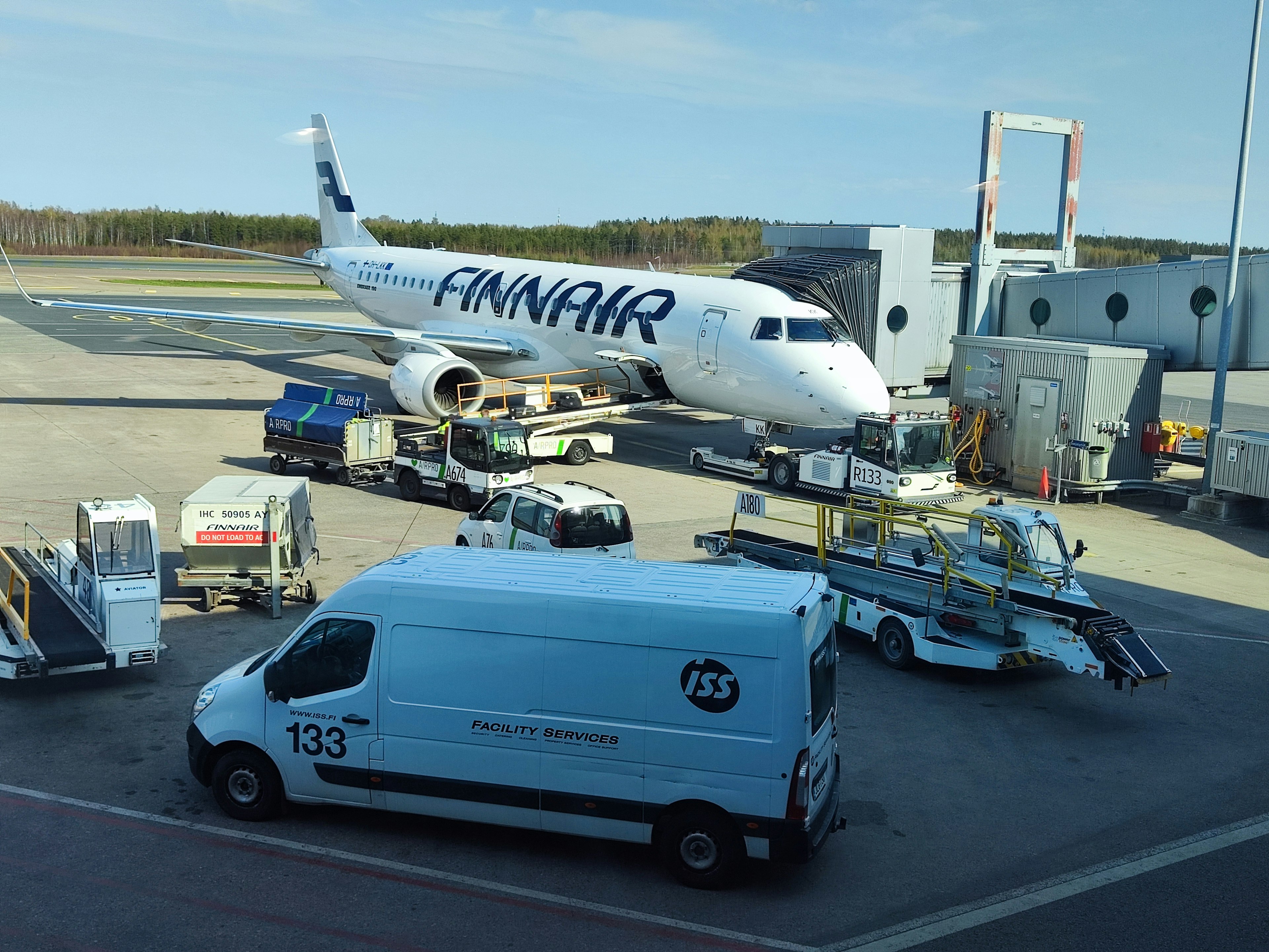 Aereo Finnair parcheggiato sulla pista con camion di trasporto e veicoli di servizio a terra nelle vicinanze