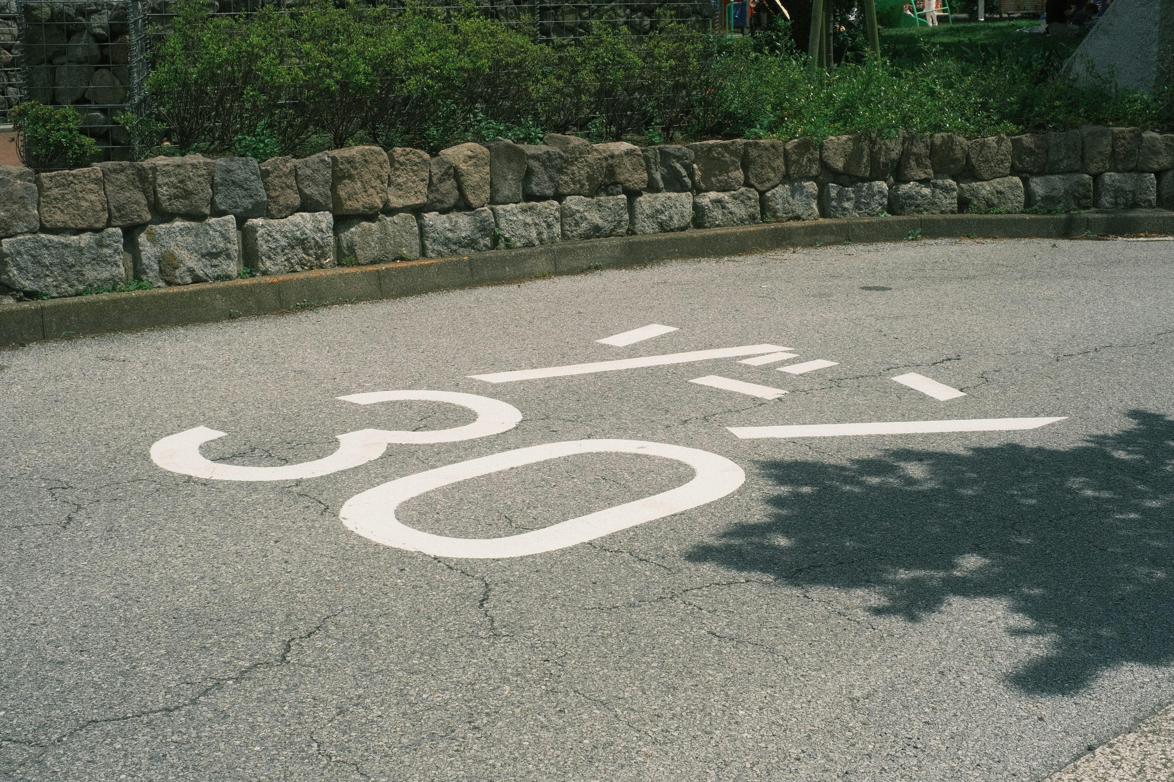 Route avec un panneau de limitation de vitesse de 30 peint et un mur en pierre