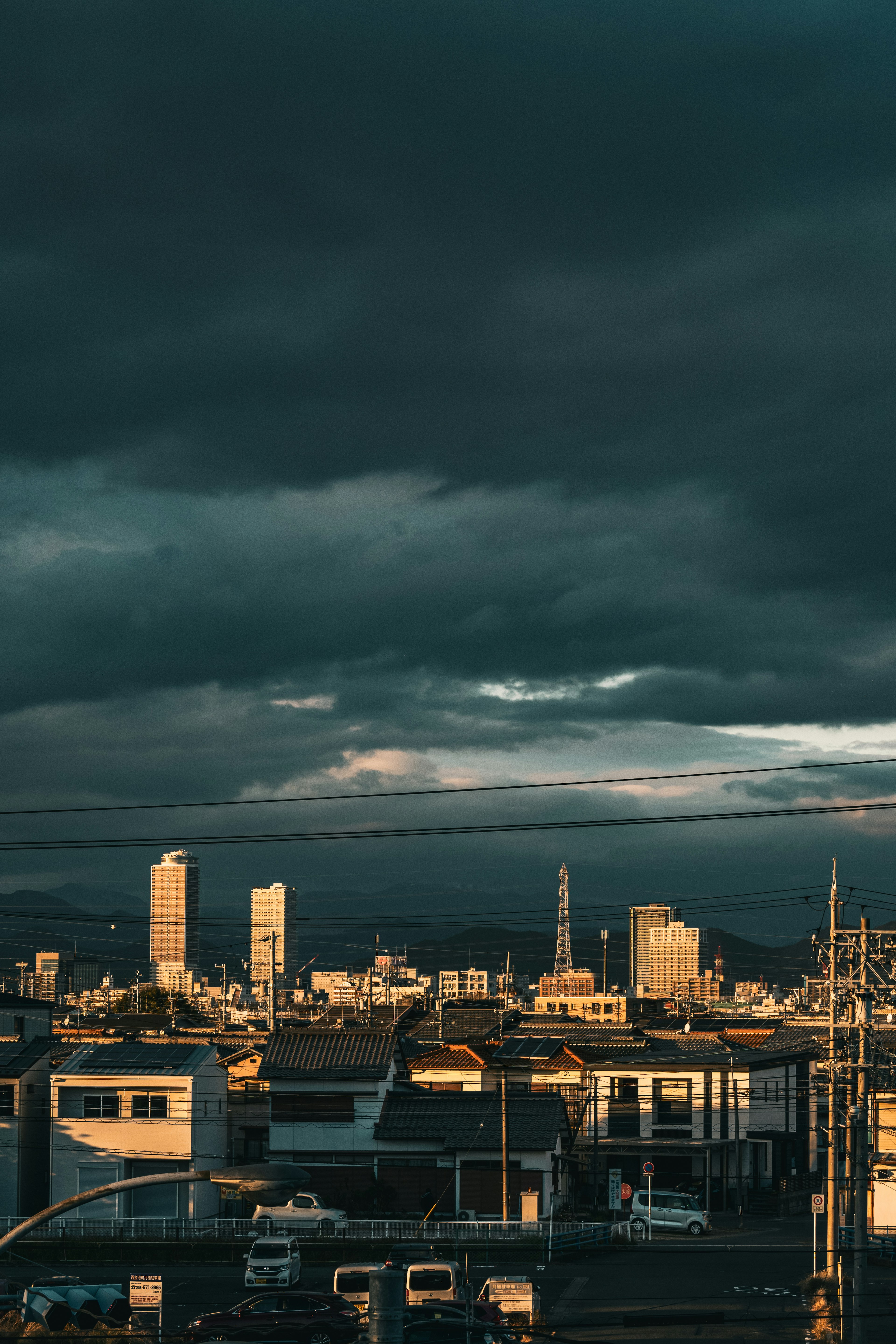 Paesaggio urbano con nuvole scure e luce del tramonto che illumina gli edifici