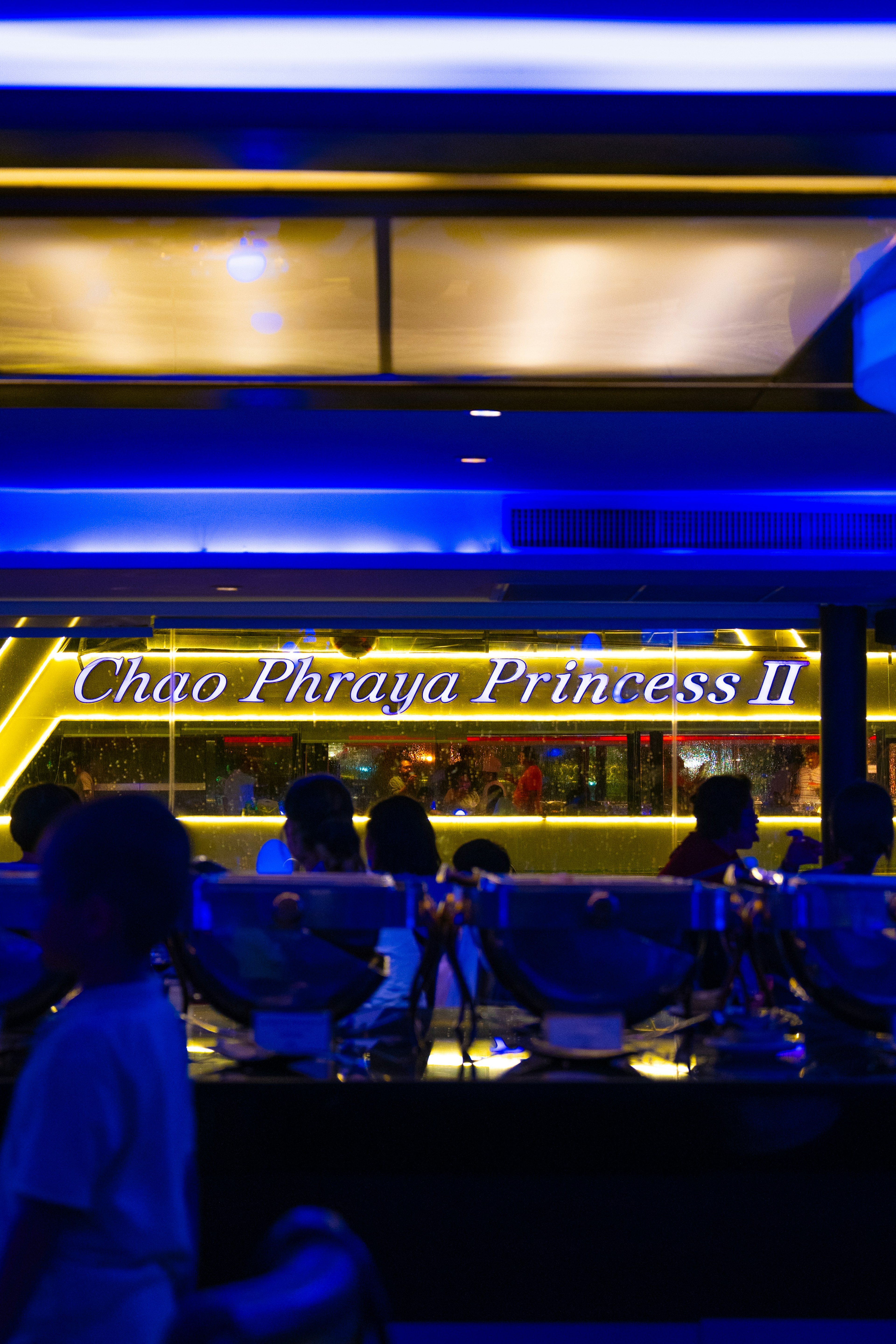 Chao Phraya Princess II-Schild, beleuchtet in Blau, mit Menschen im Blick