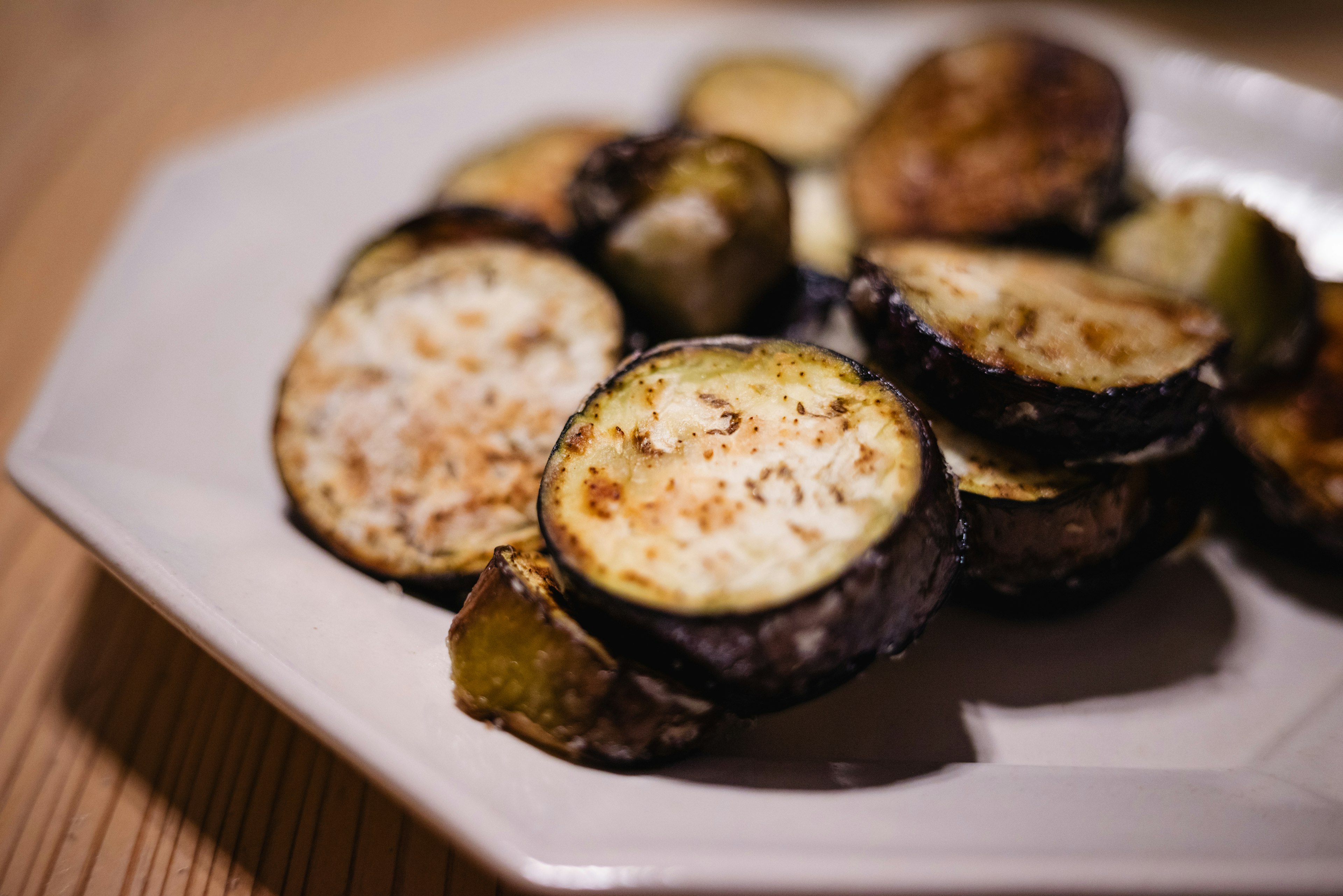 In Scheiben geschnittene gegrillte Aubergine auf einem weißen Teller