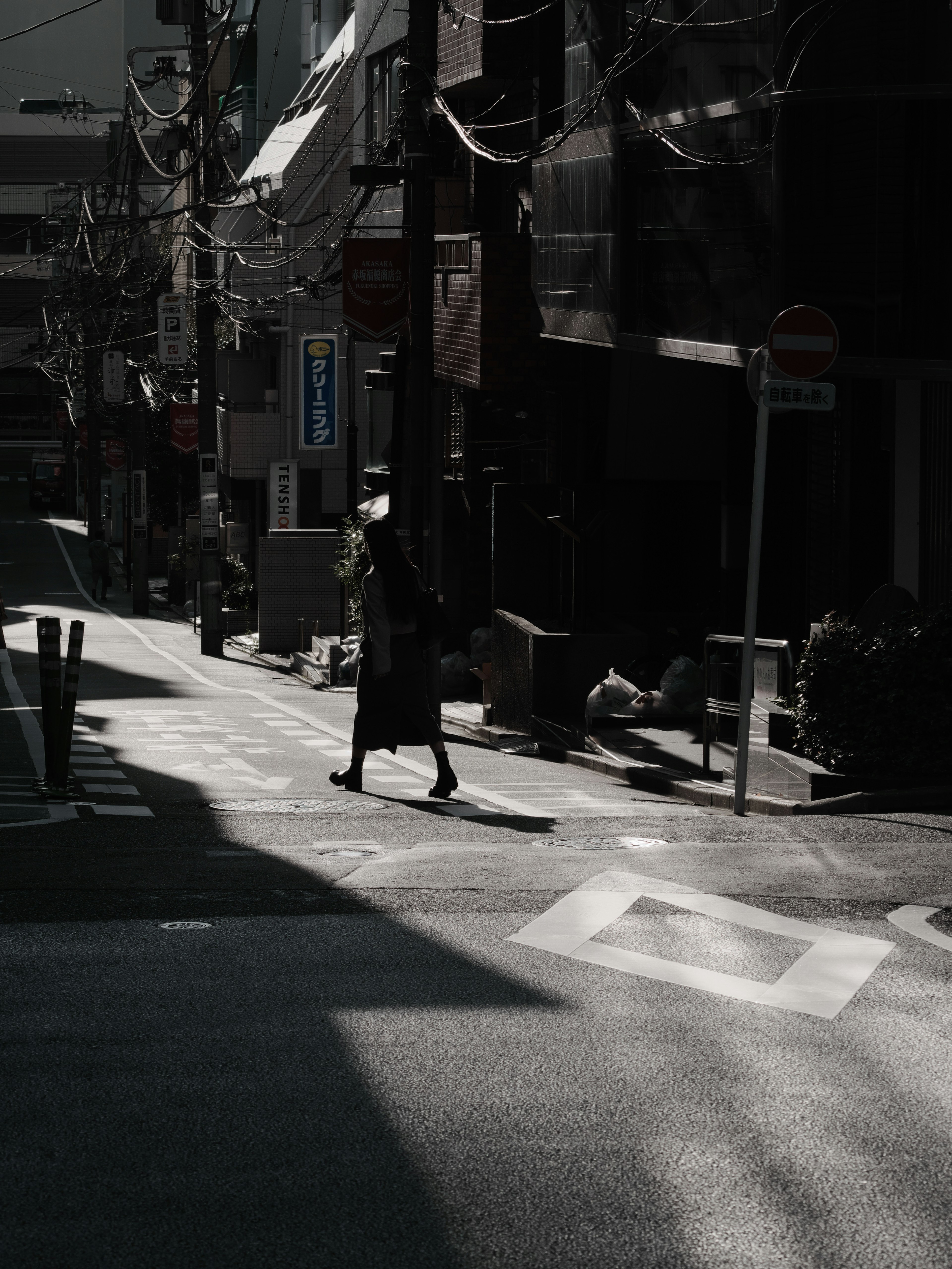 暗い通りを歩く人影と電線が印象的な都市の風景