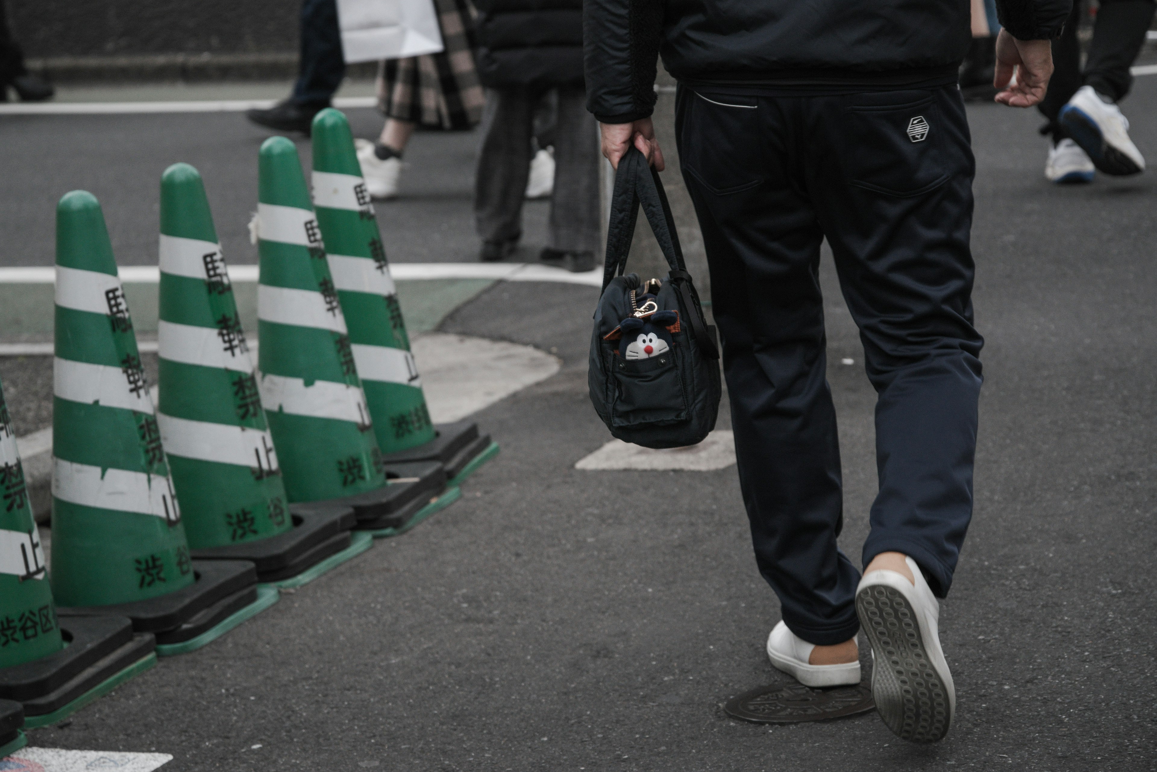 Homme marchant devant des cônes de circulation verts et blancs