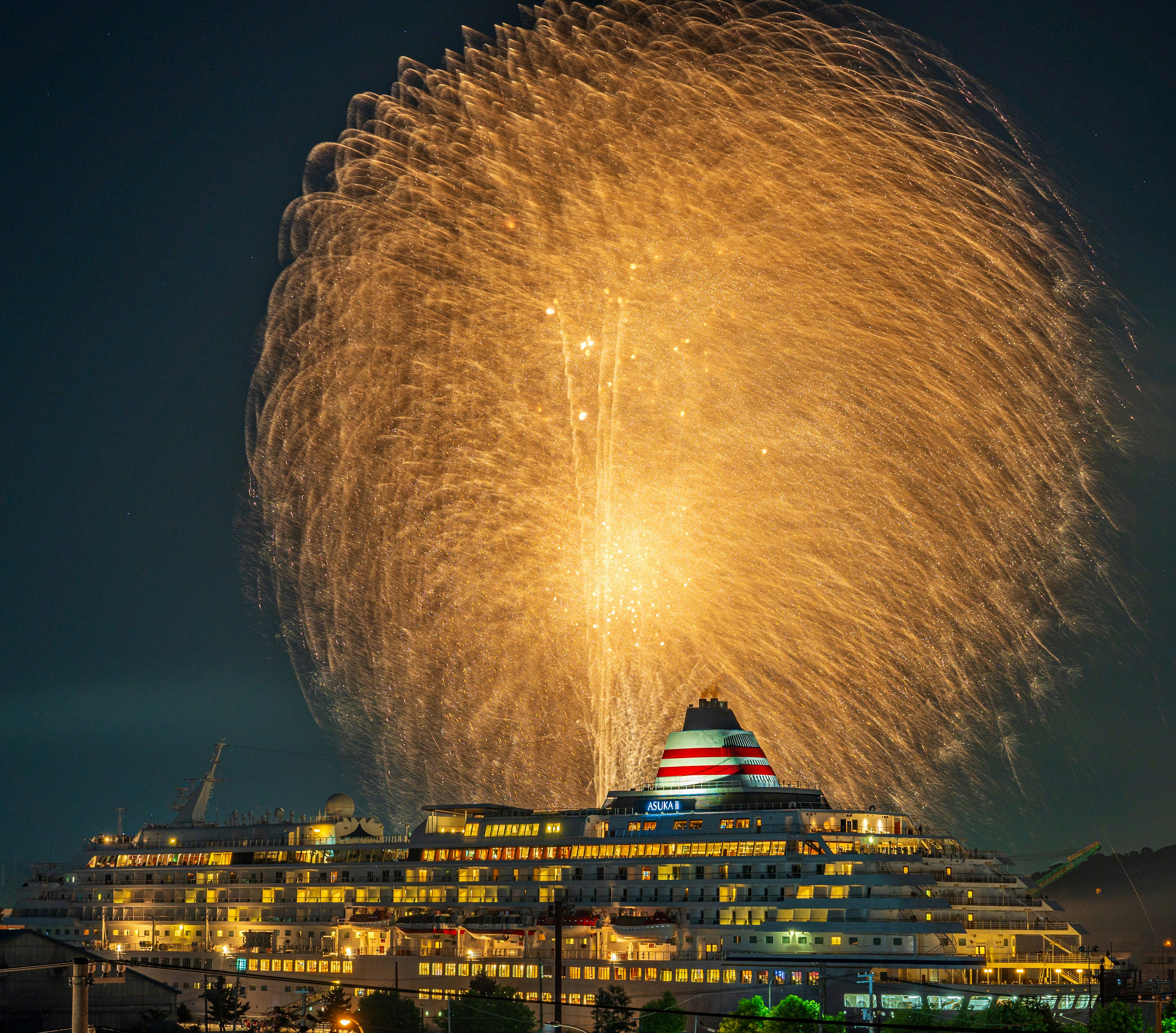 Golden fireworks burst in the night sky above a unique building