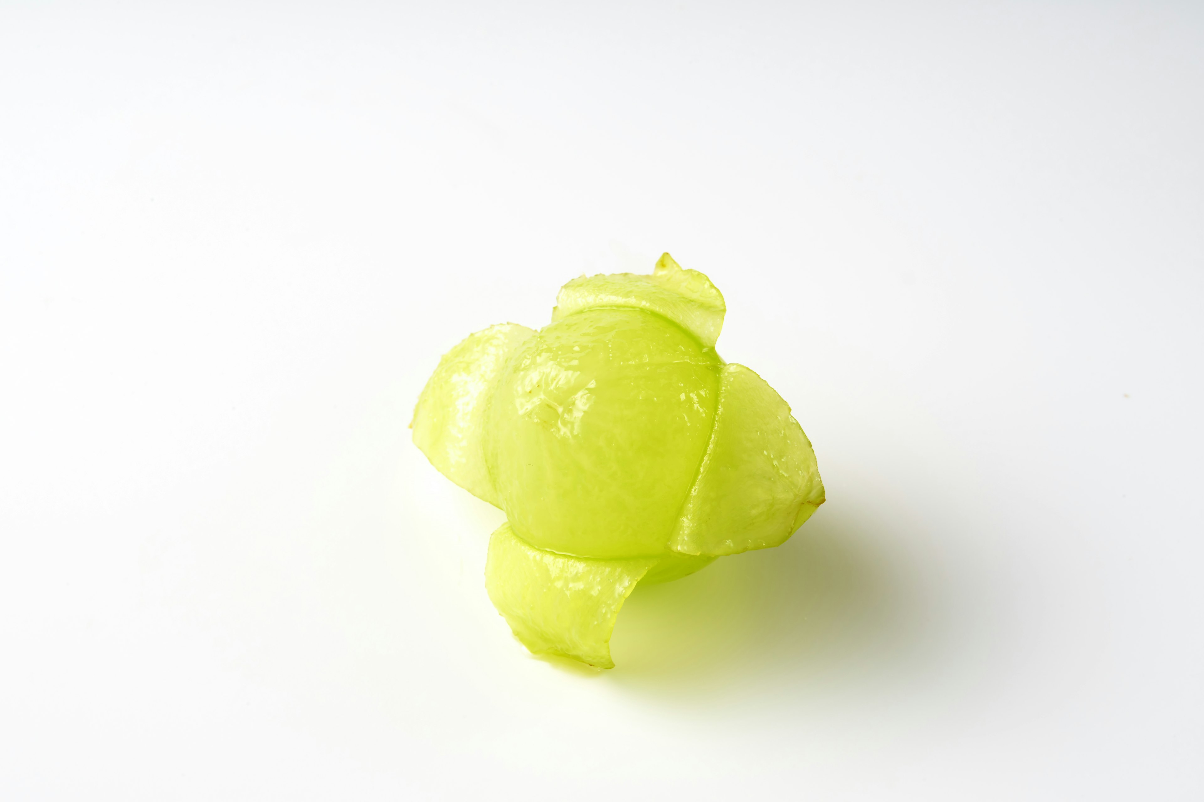 A piece of green fruit on a white background