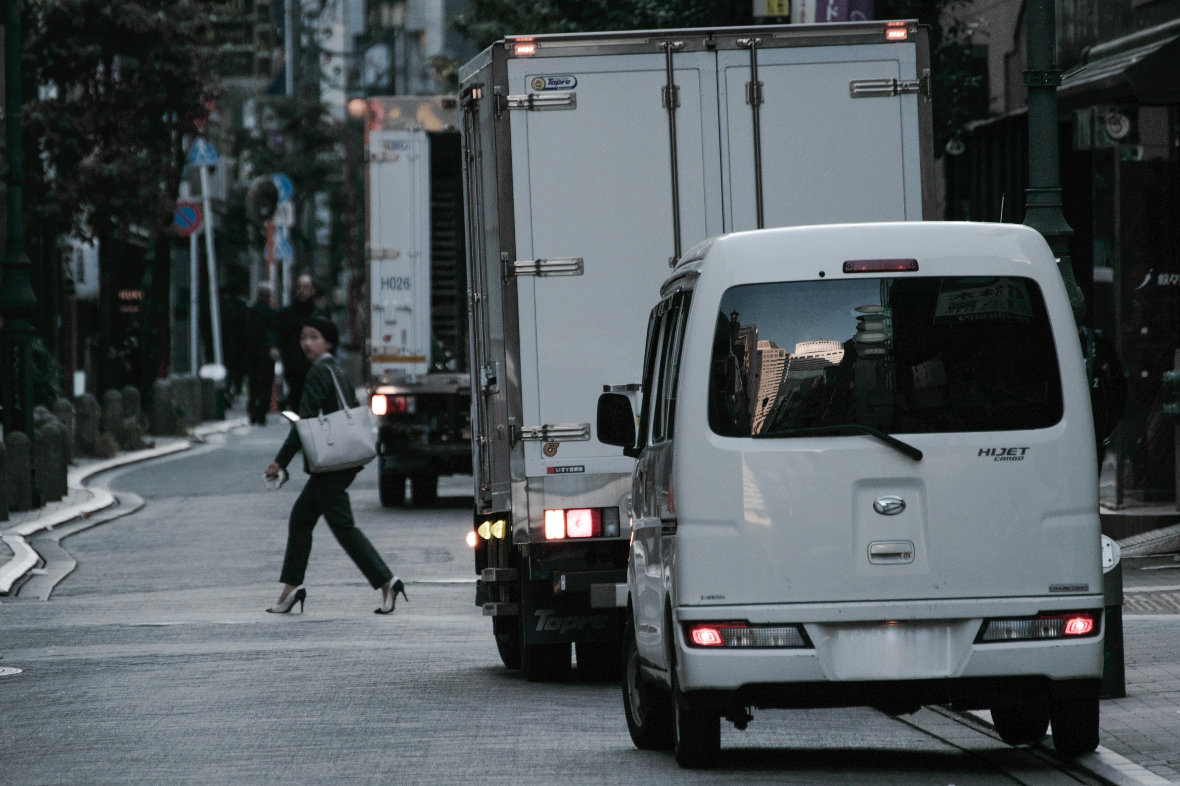 行人在白色廂型車和卡車之間穿越