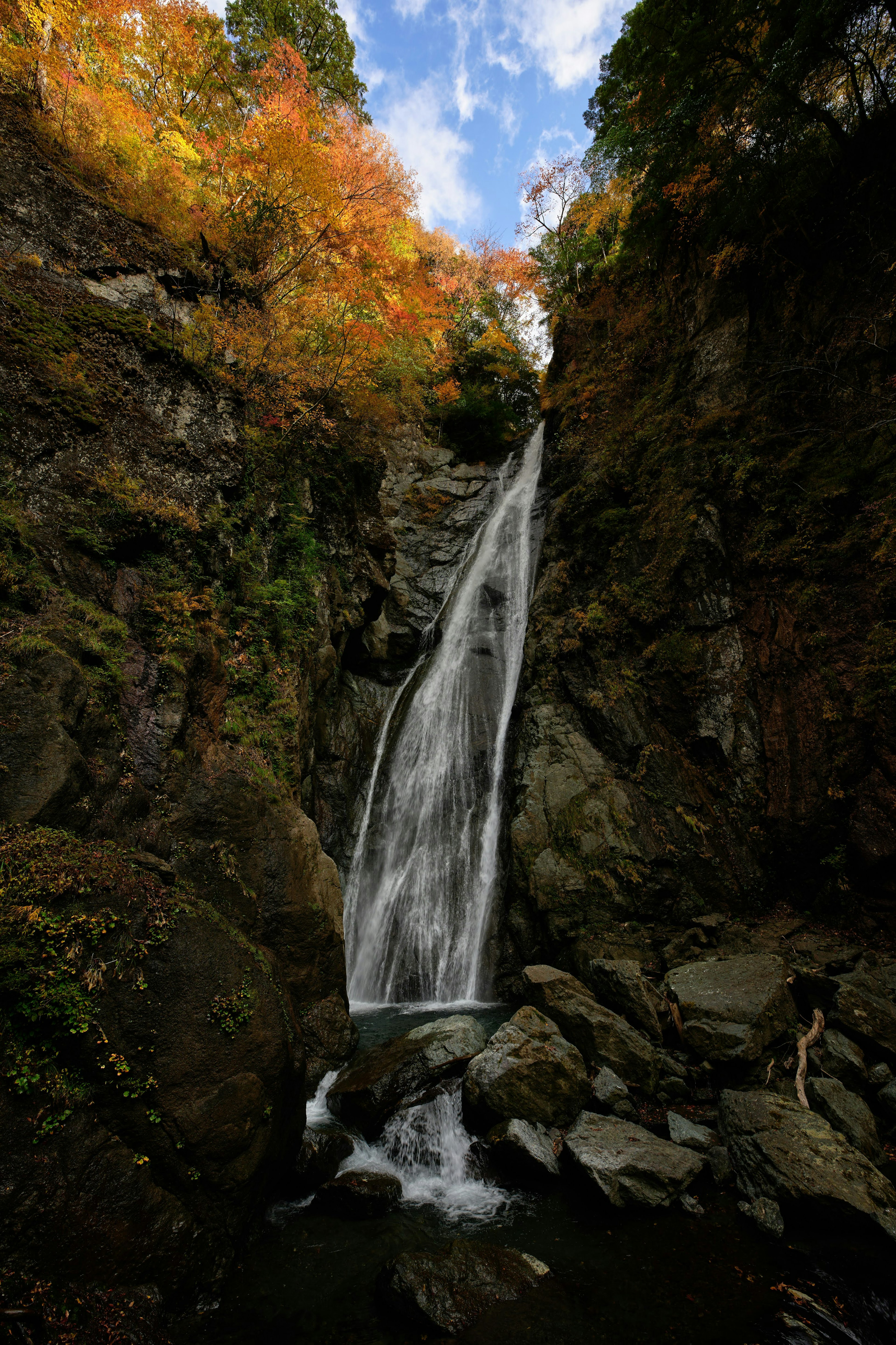 Une belle cascade tombant à travers le feuillage d'automne