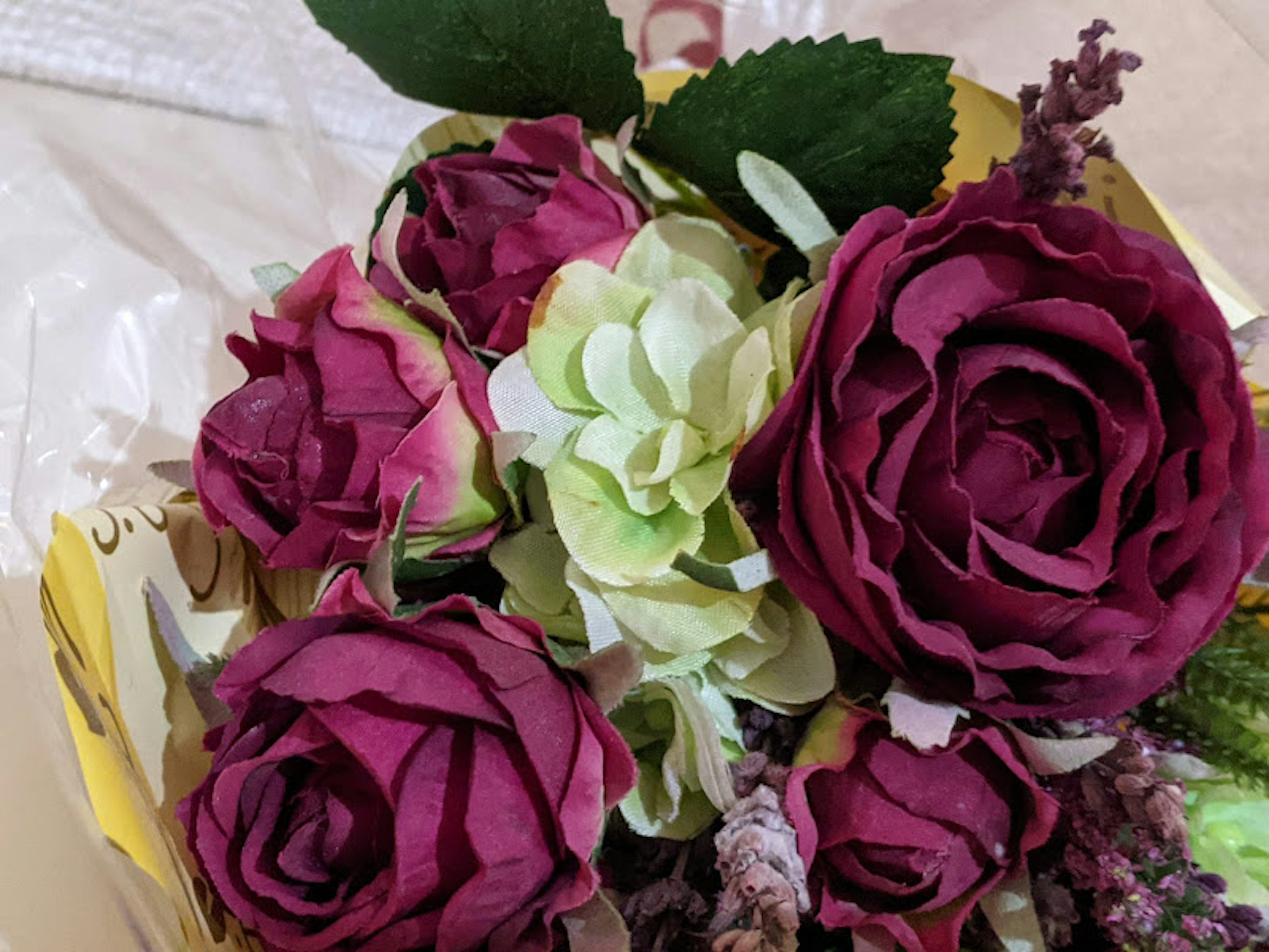 Strauß mit tiefvioletten Rosen und grünen Blumen