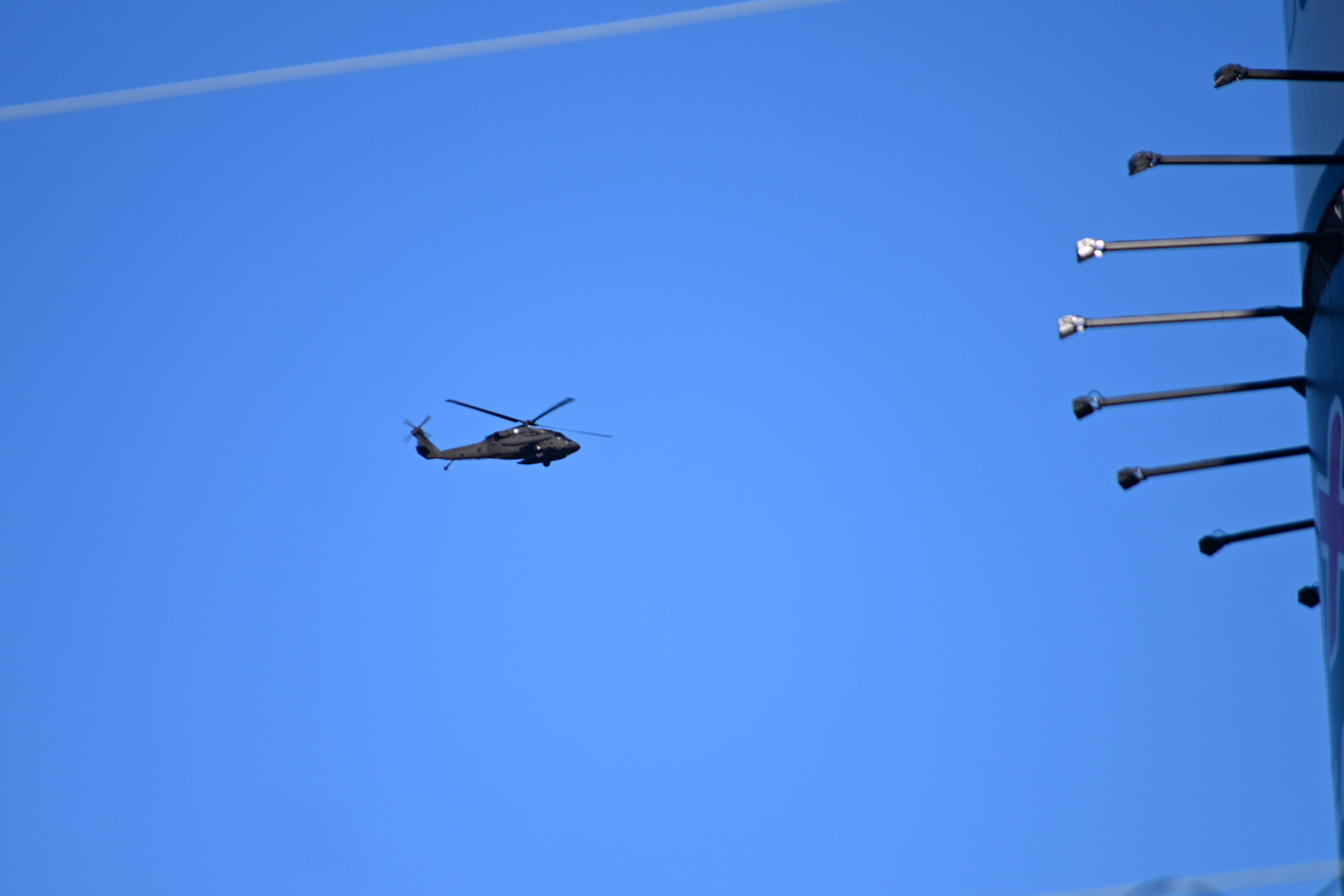 Helicóptero volando contra un cielo azul claro con estructuras circundantes