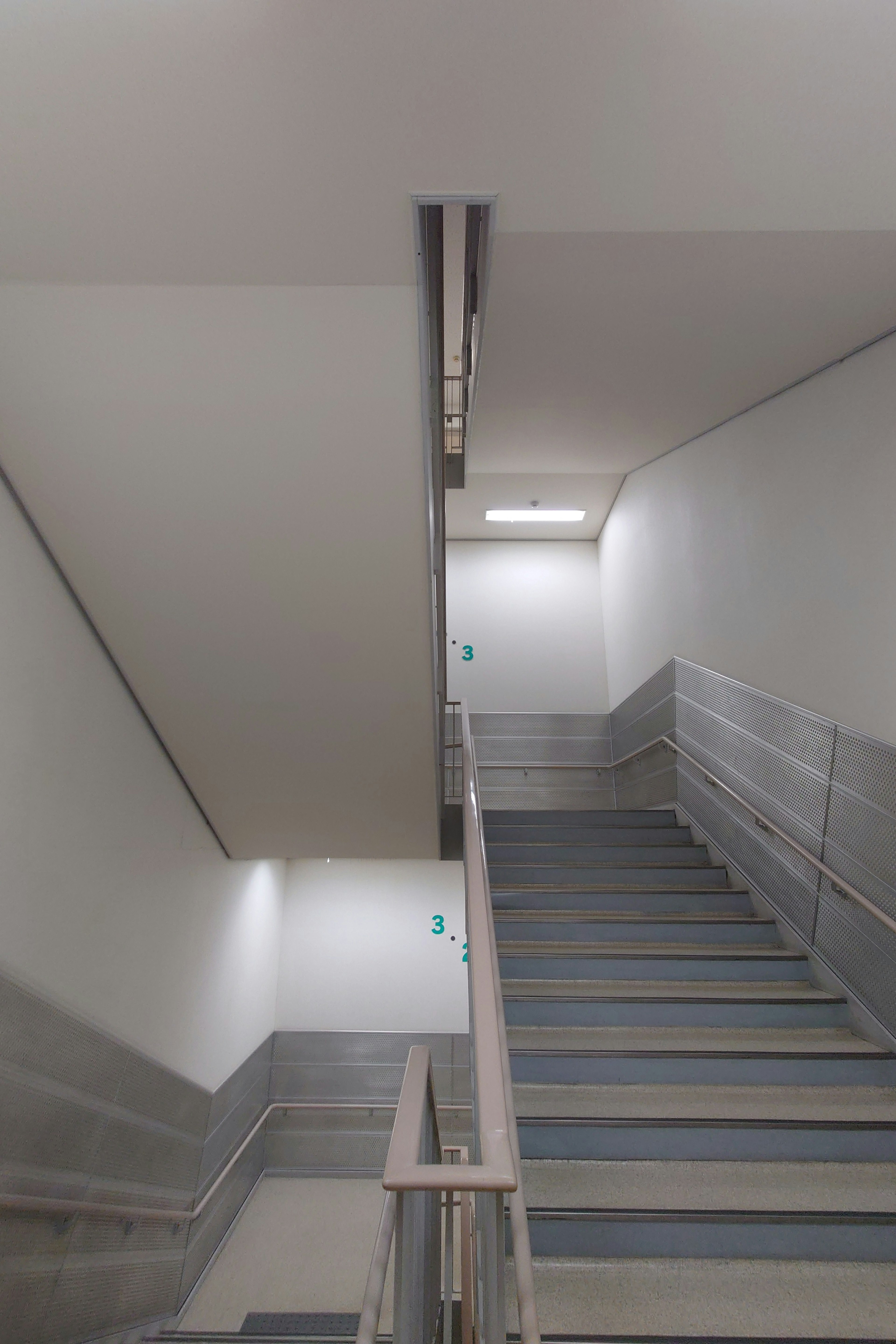 Escalier intérieur simple avec des murs blancs et des rampes en métal