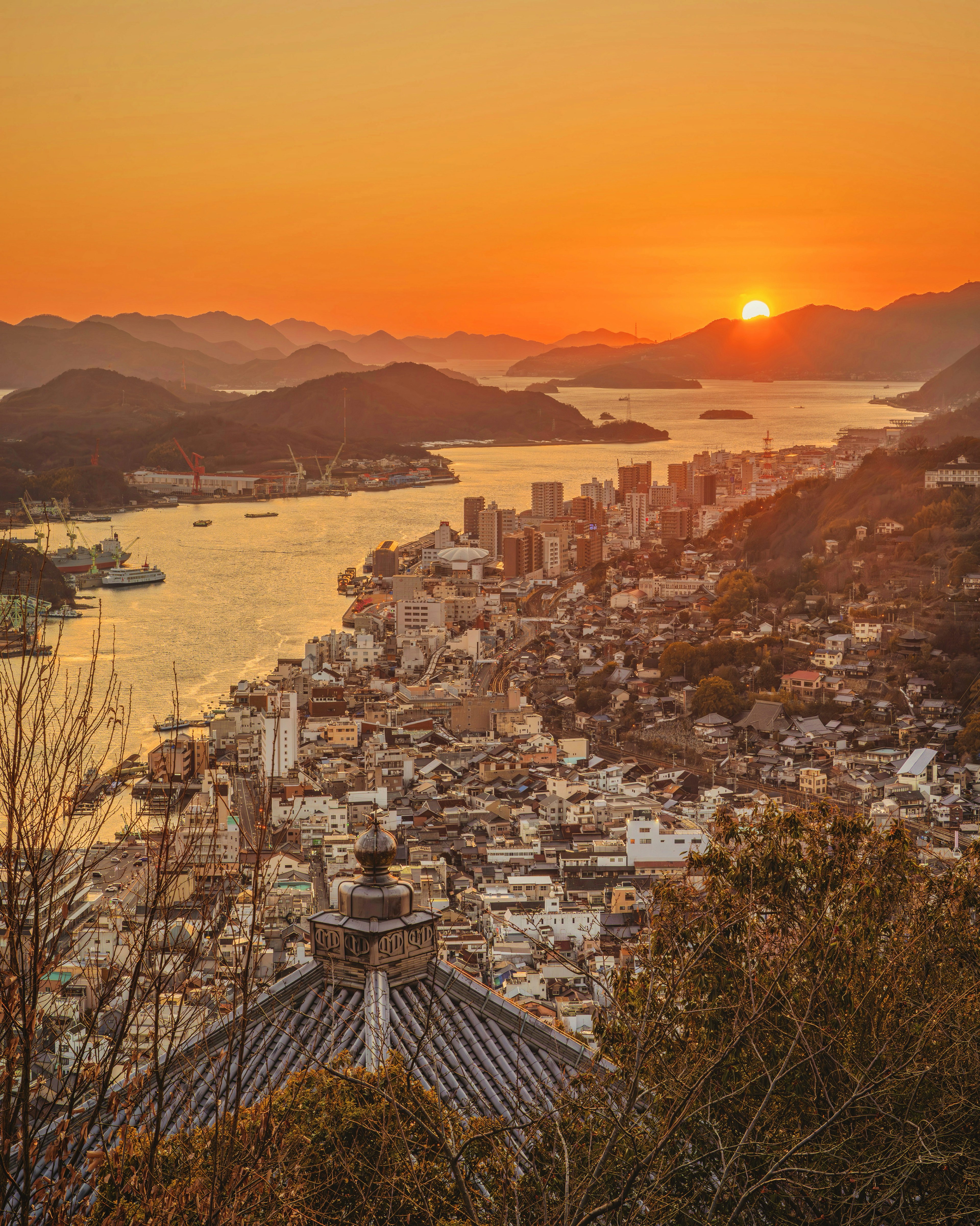 Panorama della città e del mare al tramonto con cielo arancione vibrante