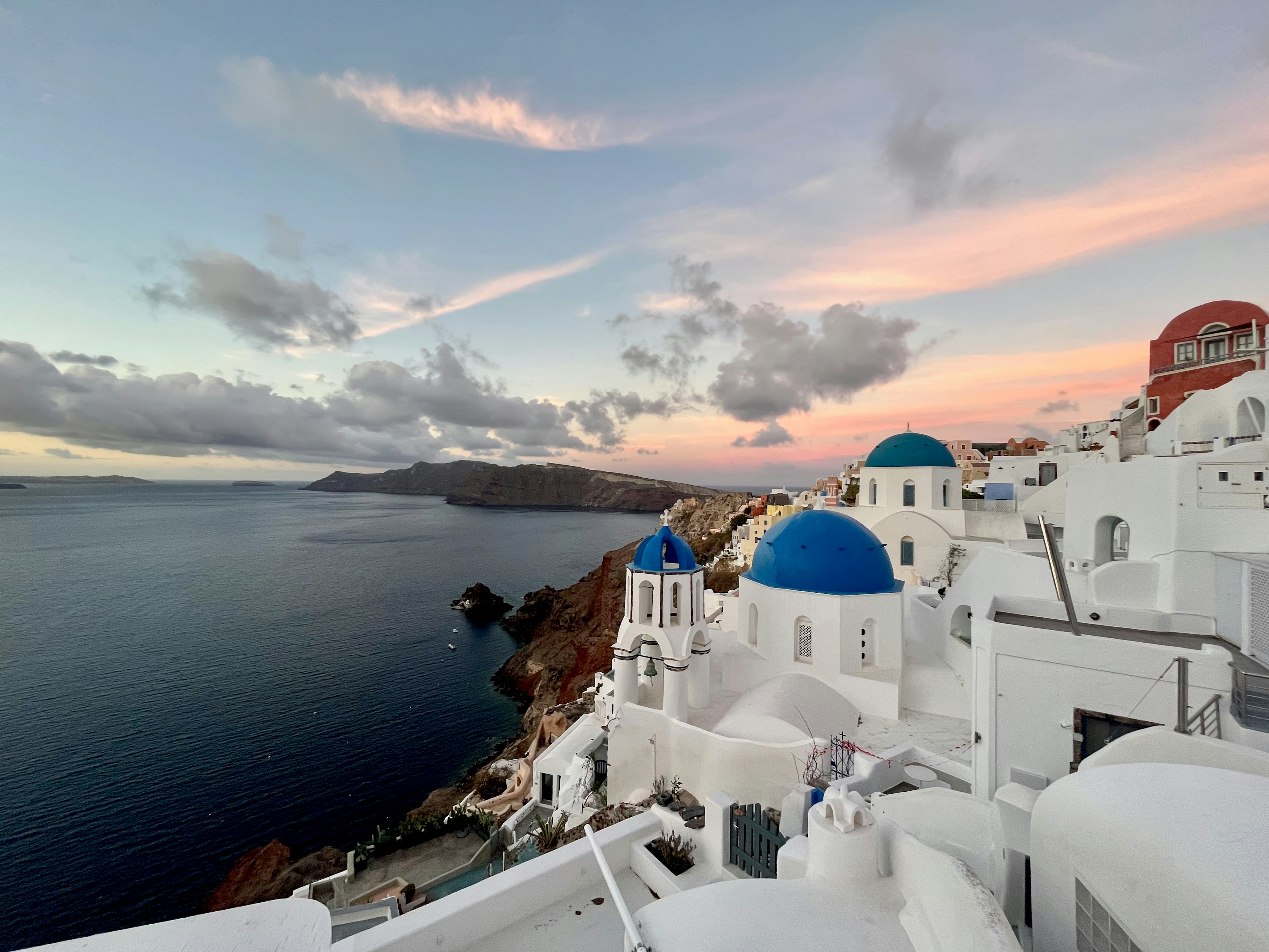 Schöne Meeresansicht von Santorin mit weißen Gebäuden und blauen Kuppeln unter einem Sonnenuntergangshimmel