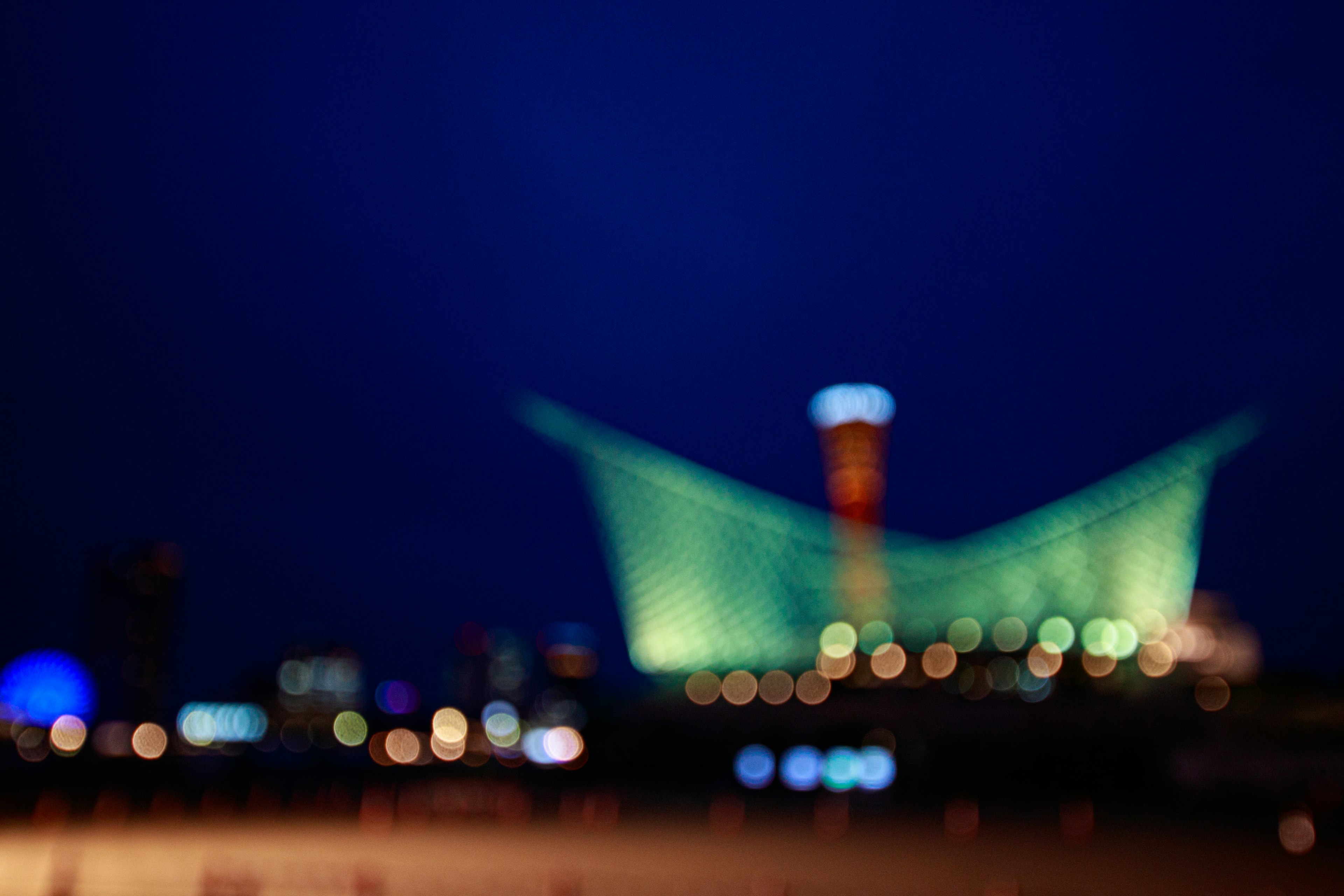 Paysage urbain flou de nuit avec un bâtiment vert et des lumières vives