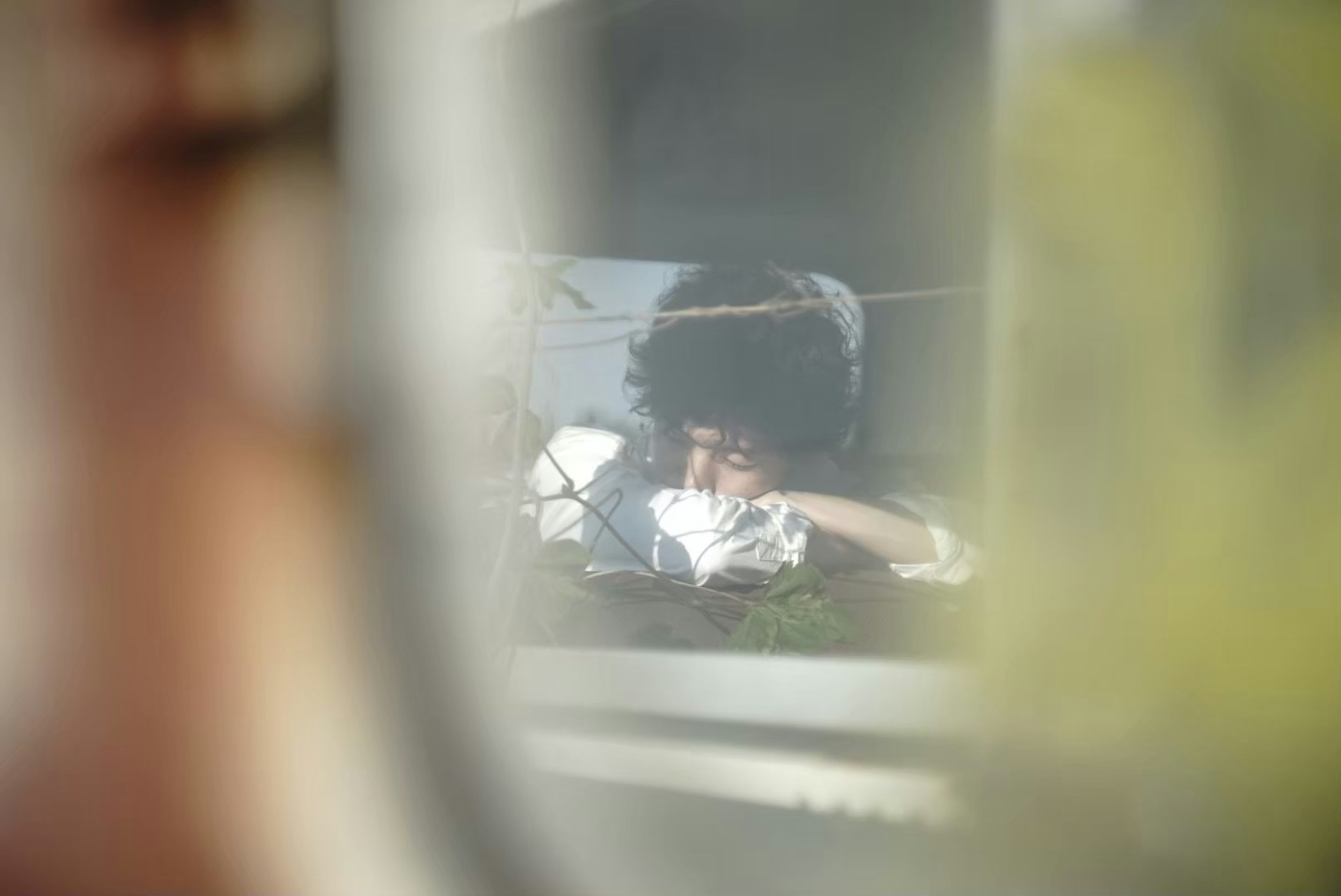 A person holding a tissue seen through a window