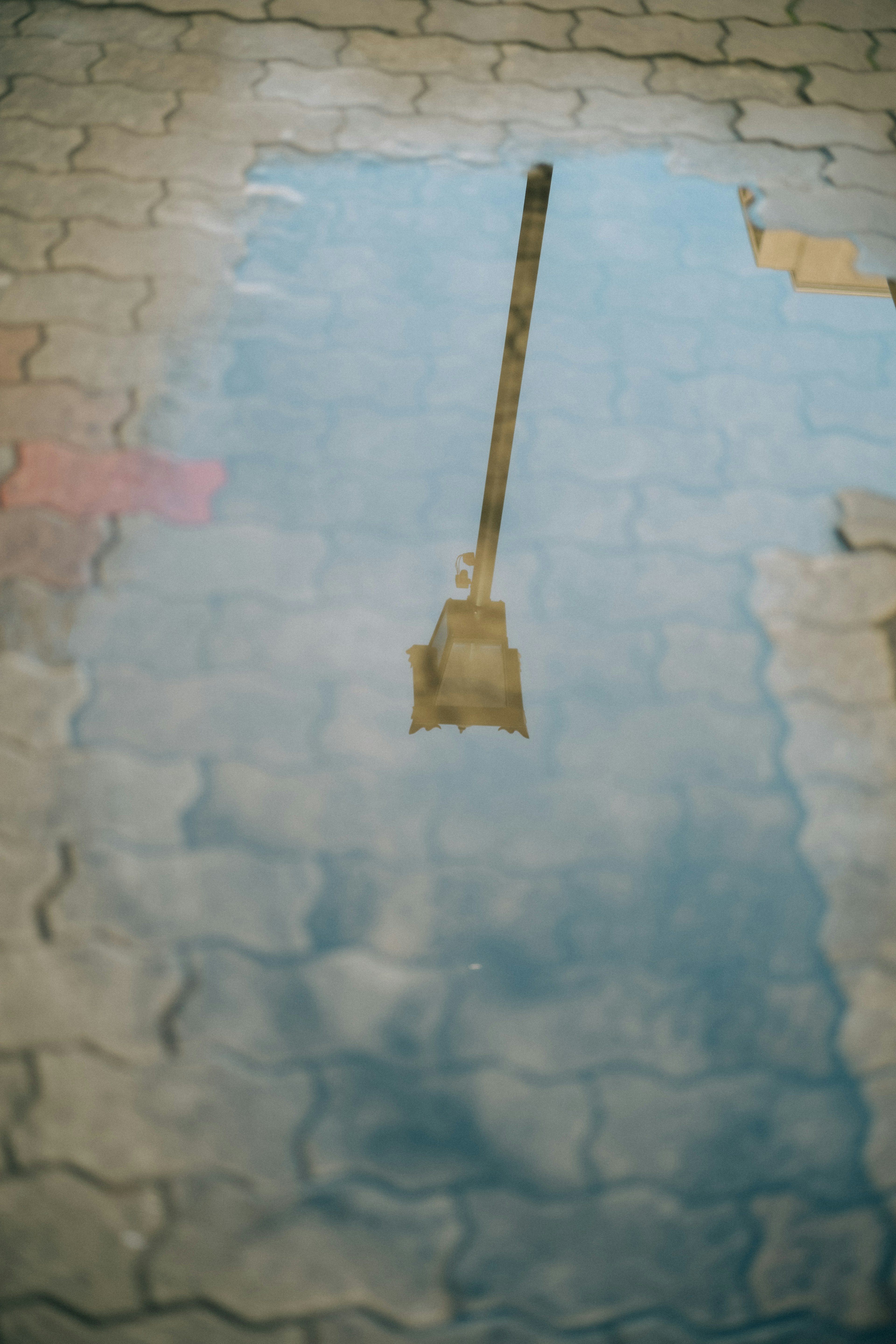 Reflejo de una farola en un charco sobre adoquines