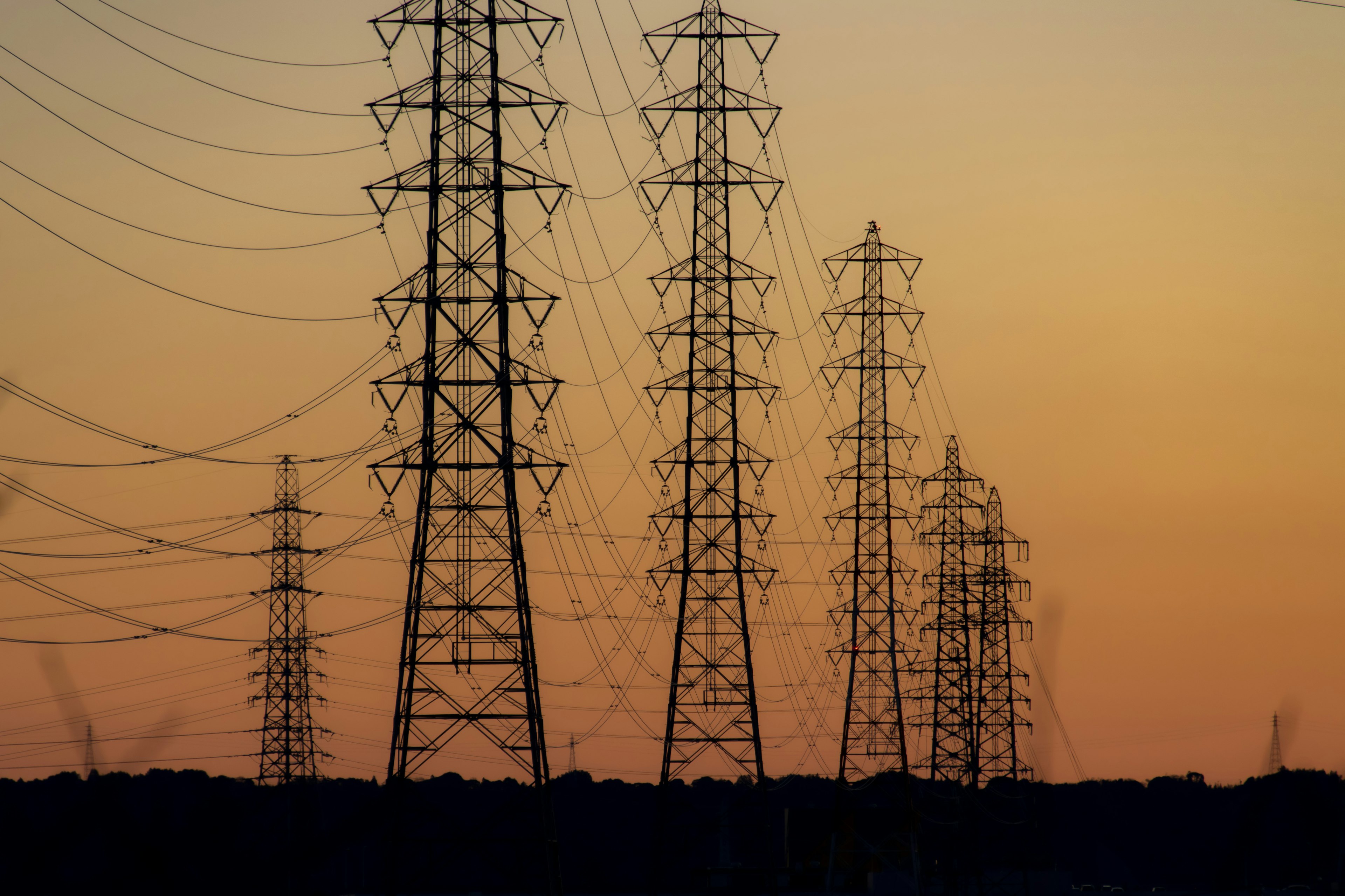 Silhouette of power towers against a sunset sky