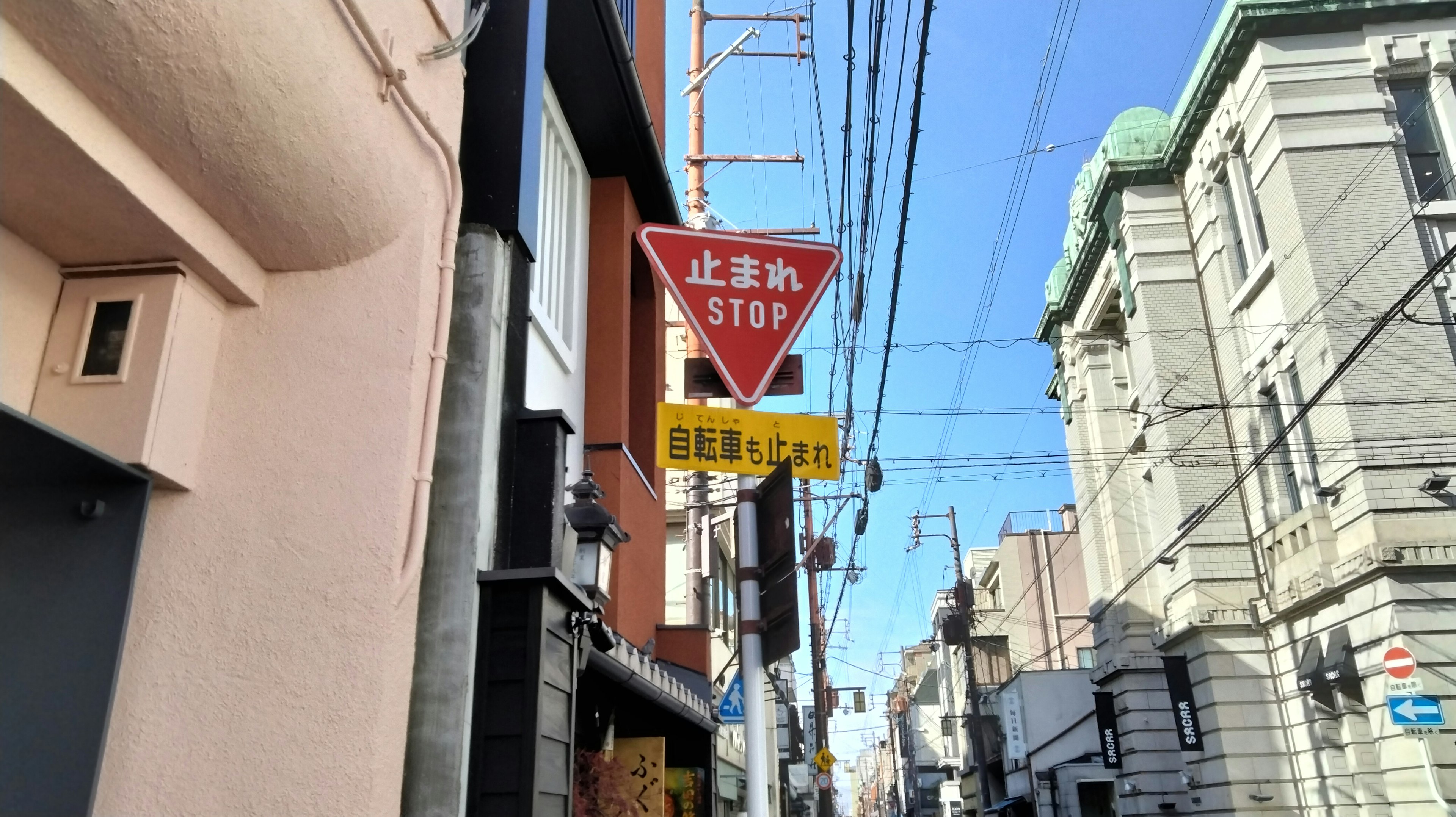 赤い止まれの標識と青い空の下の街並み