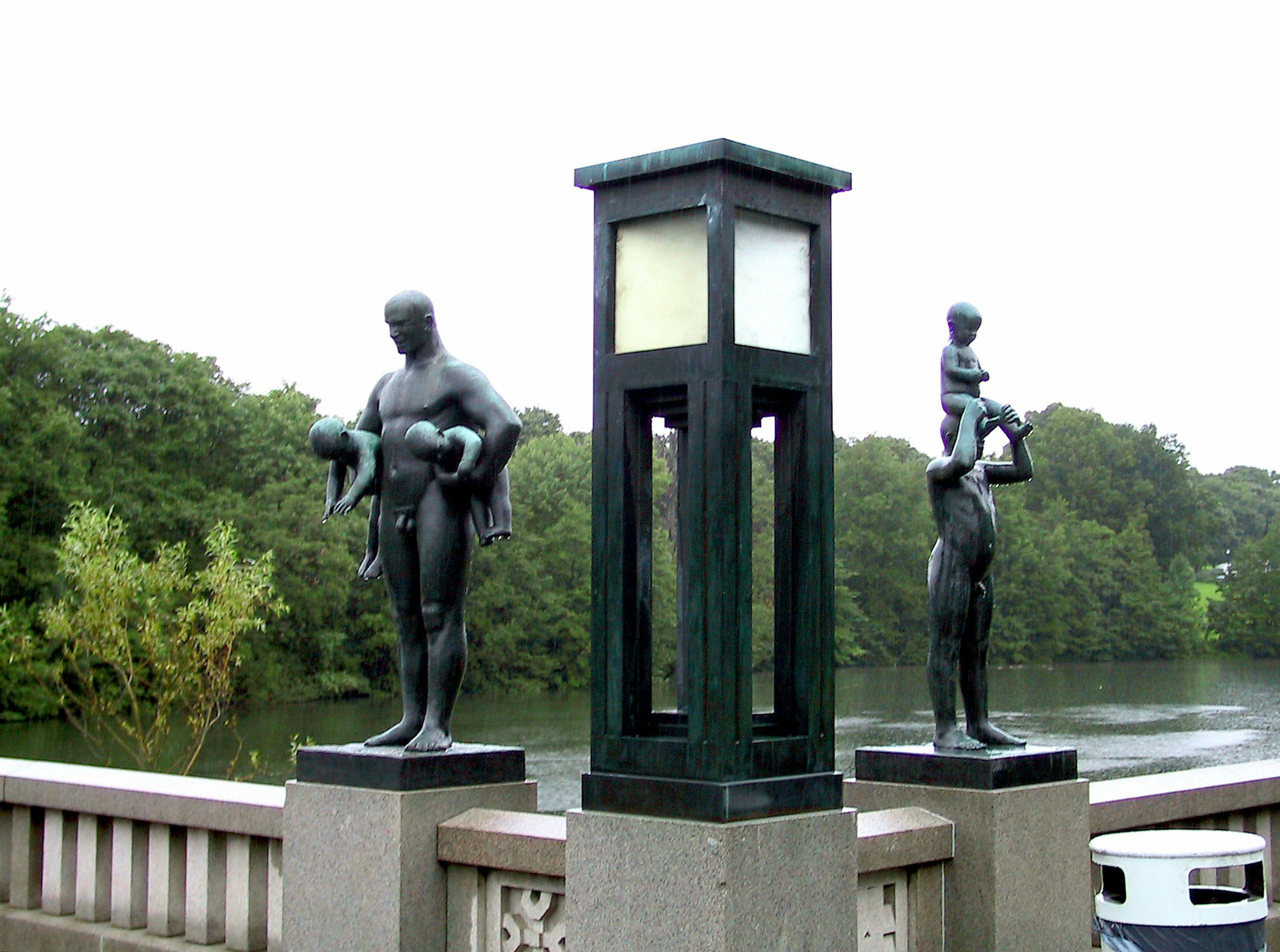 Sculptures en bronze de figures tenant des enfants à côté d'un lampadaire près d'une rivière