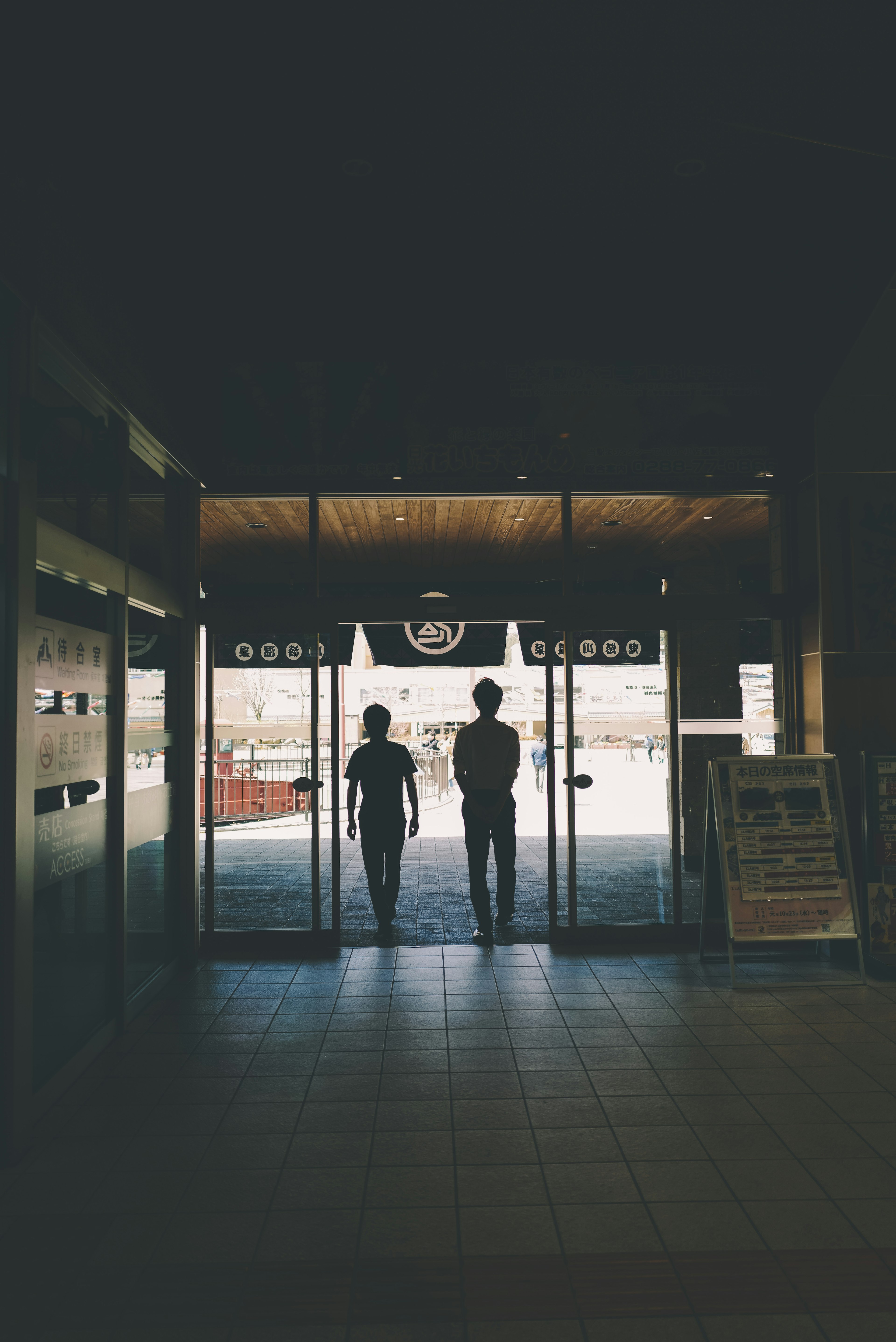 Two people walking out through automatic doors