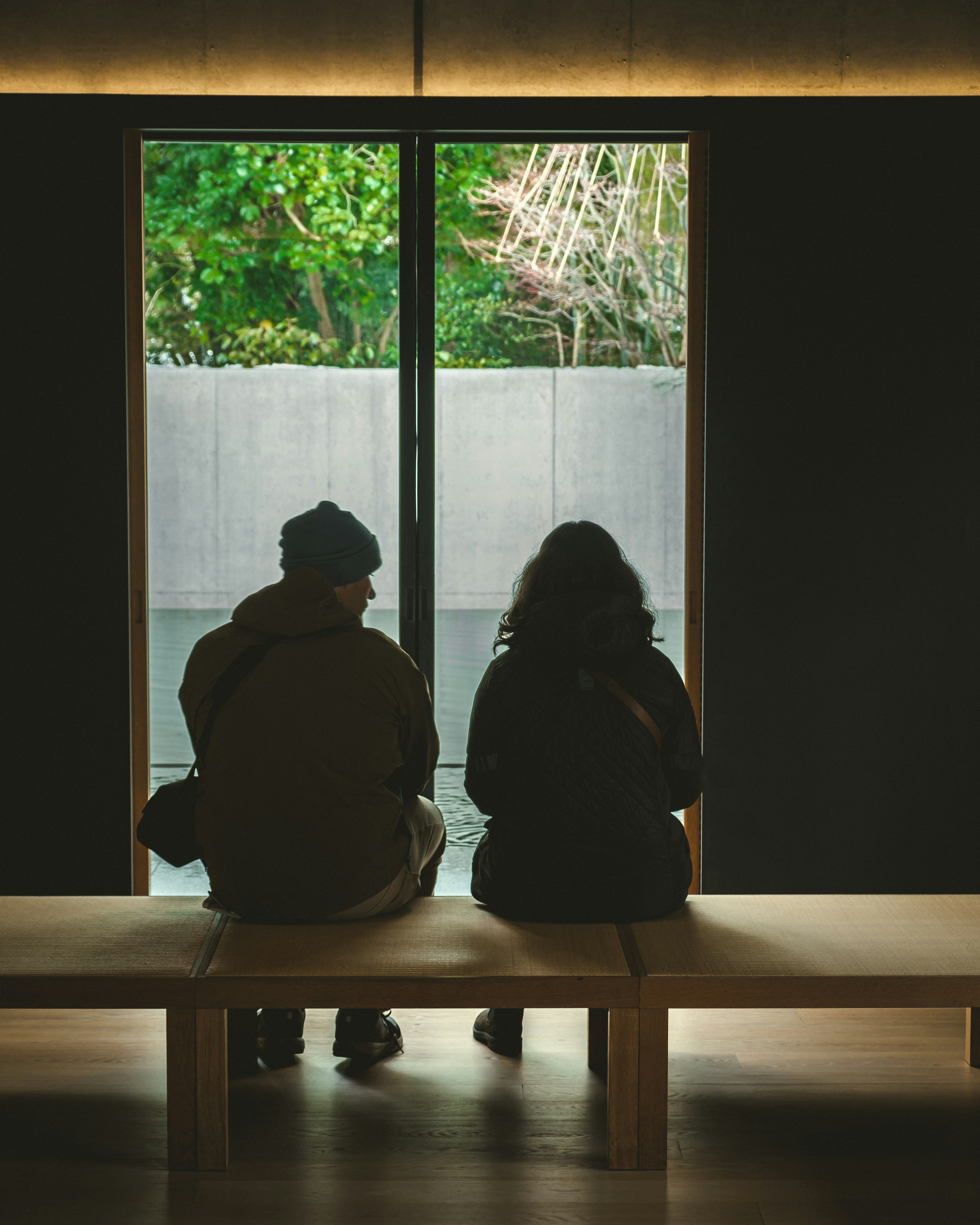 Dos personas sentadas frente a una ventana con vista a la vegetación