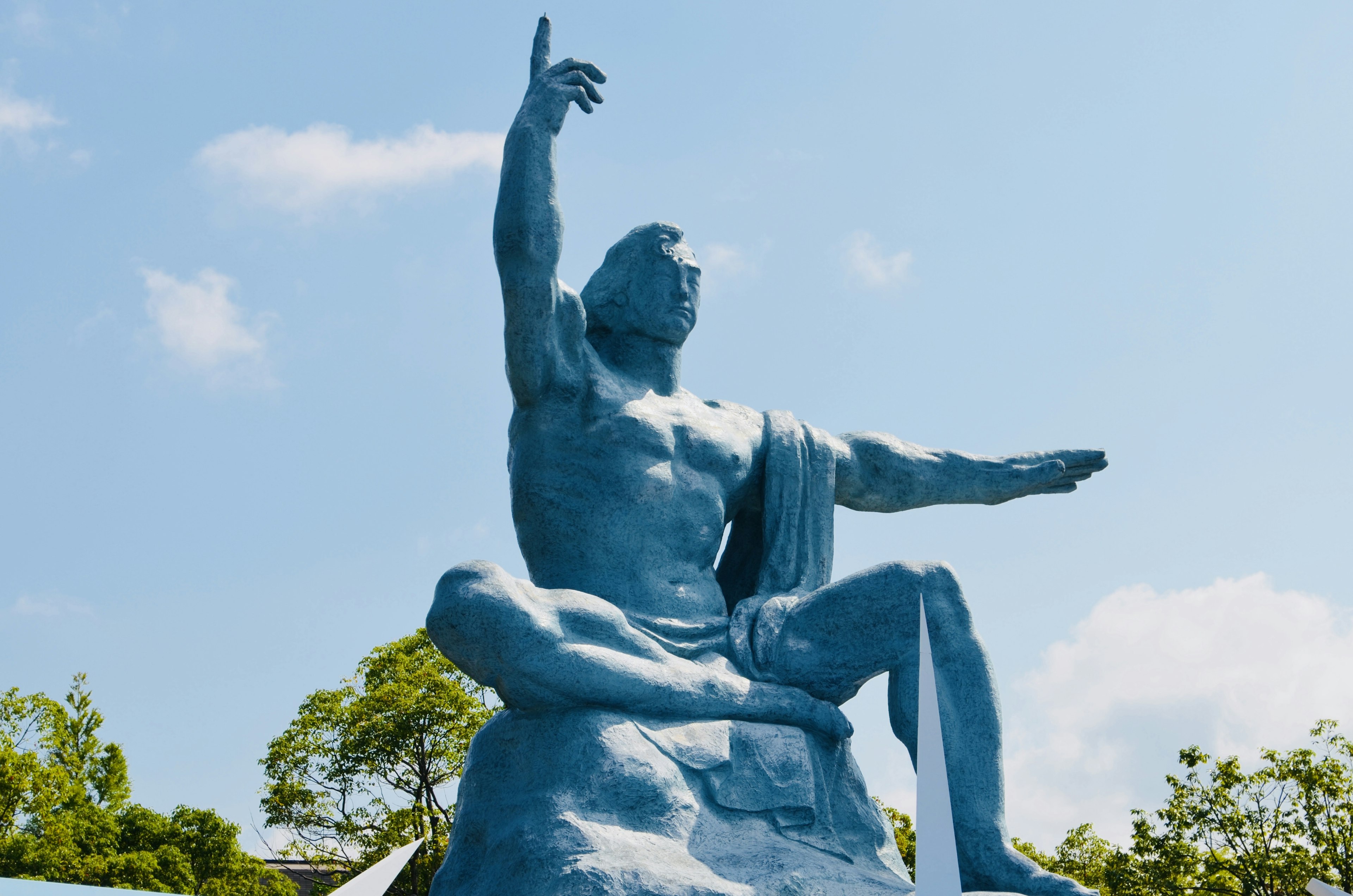 A blue statue reaching towards the sky