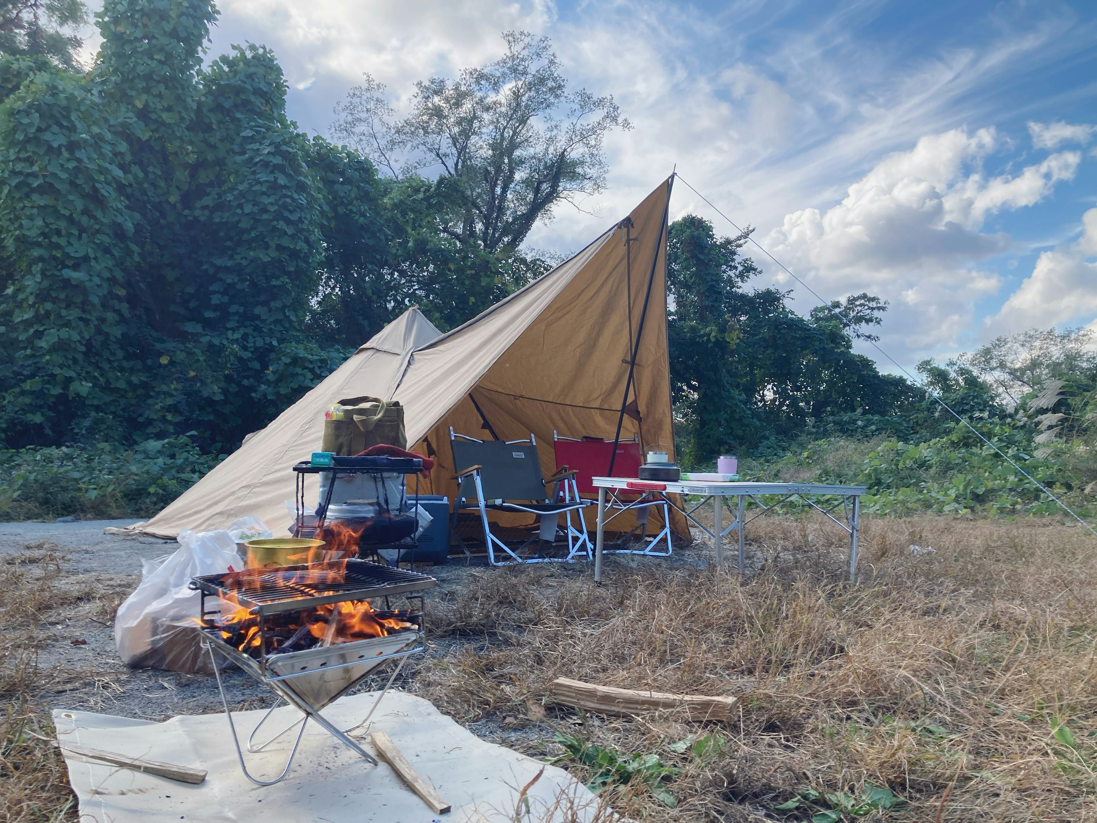 Tenda besar yang dipasang di lokasi perkemahan dengan api yang menyala di dekatnya