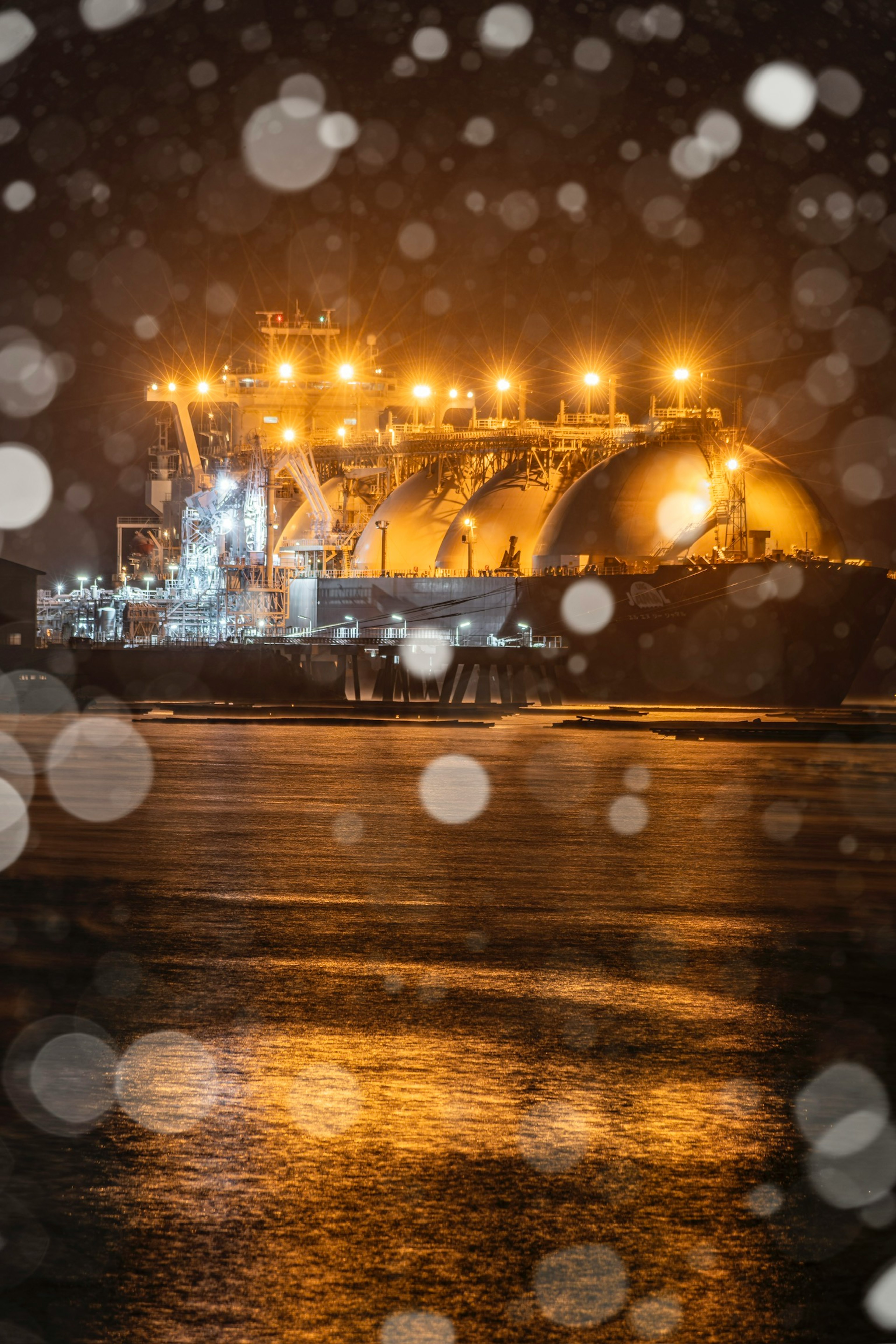 Navire de transport de GNL lumineux flottant sur la mer la nuit