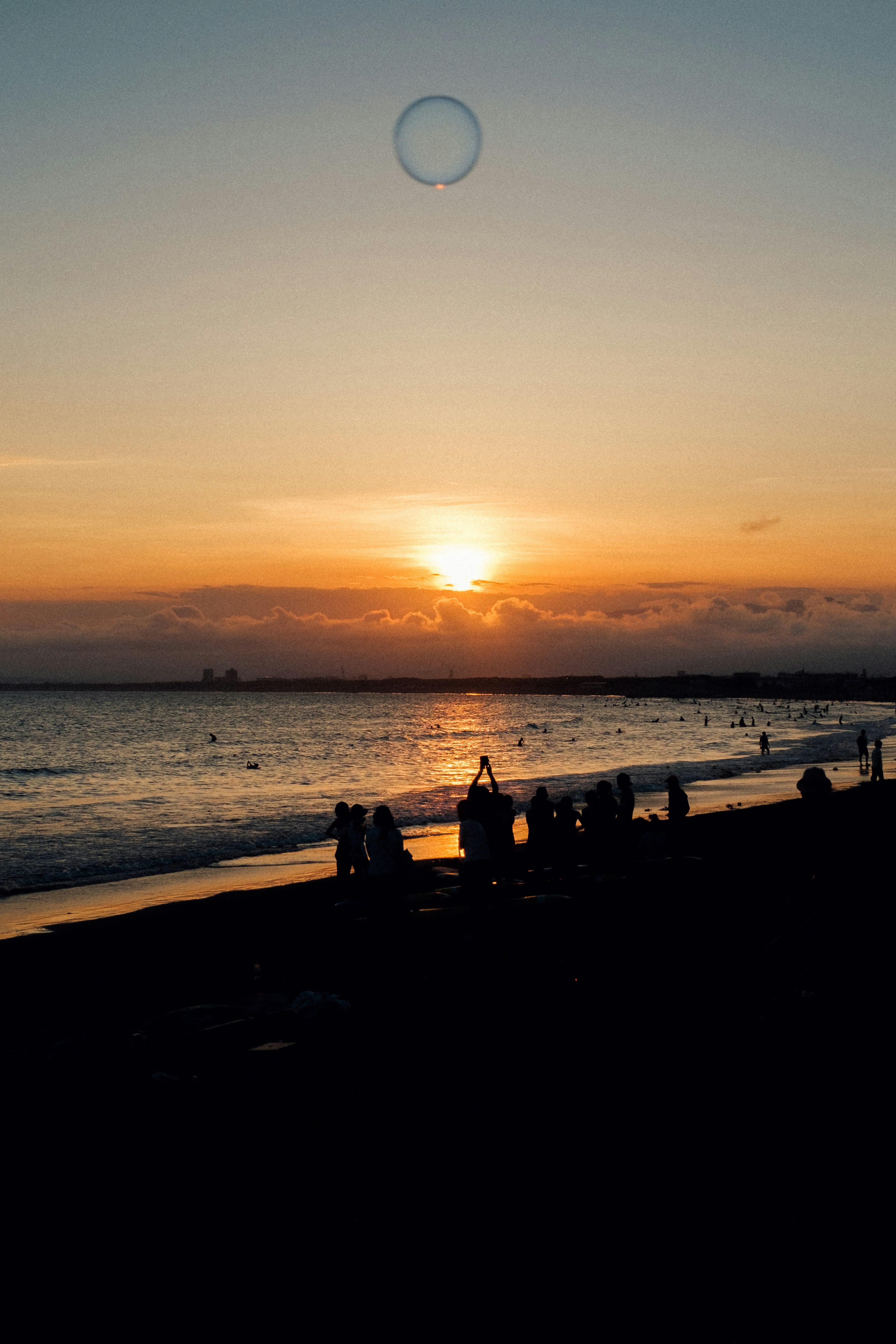 夕日が沈むビーチの風景 人々が海岸に立っている