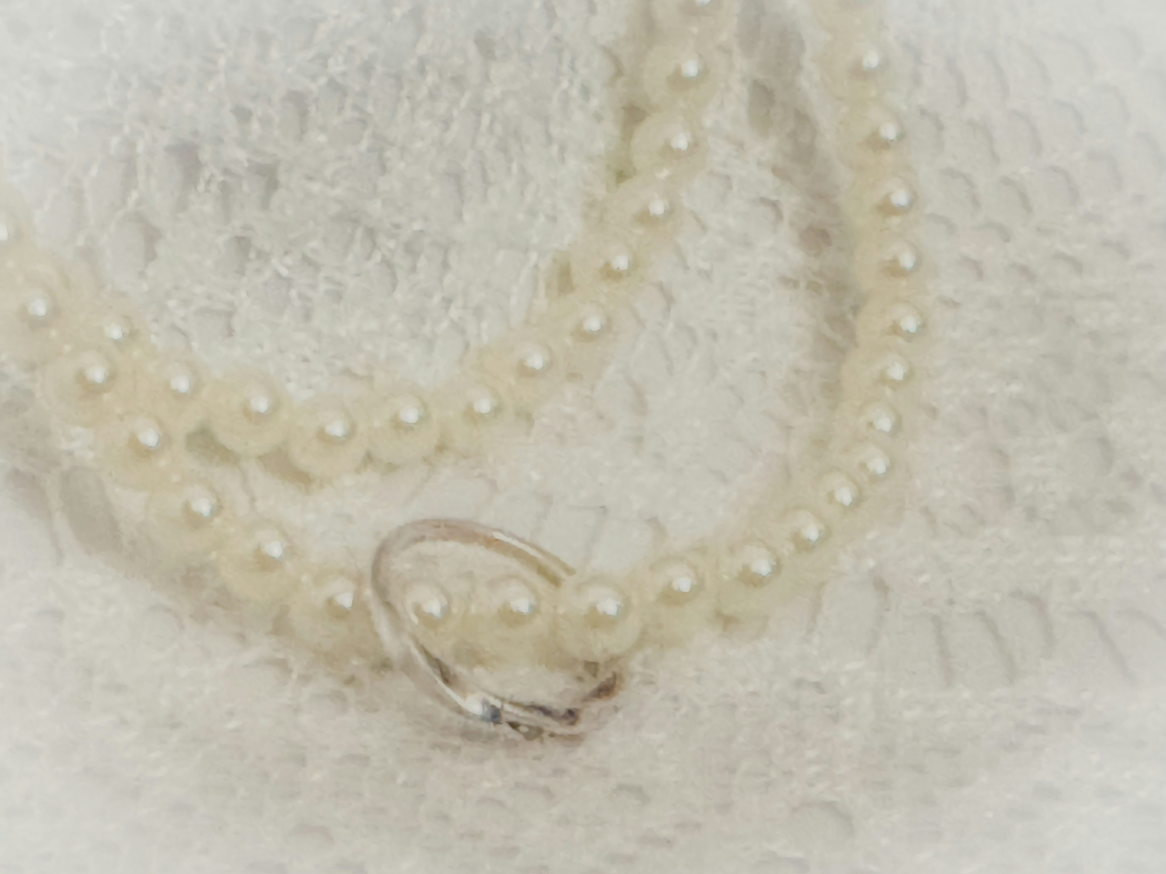 Pearl necklace resting on white lace fabric