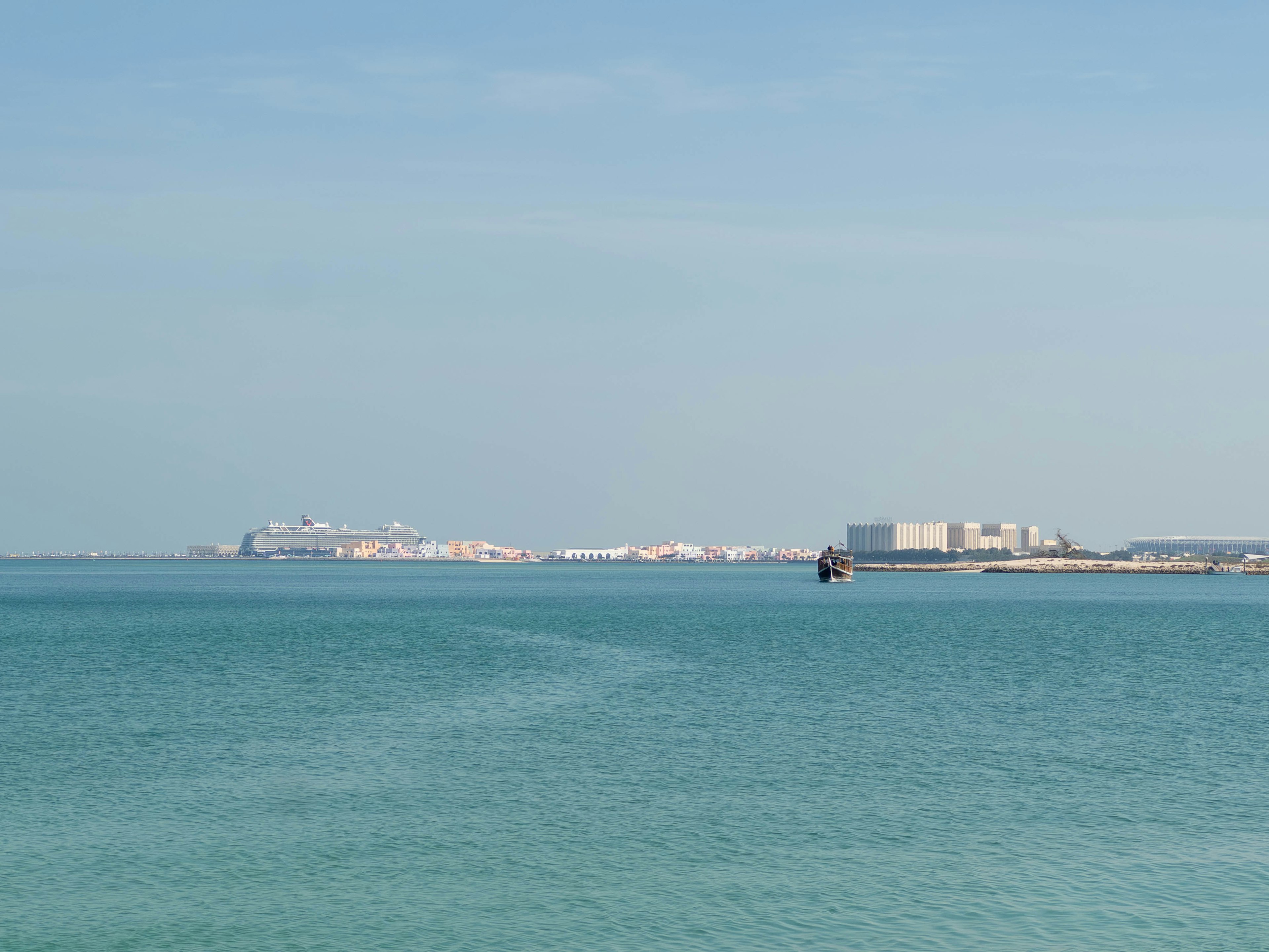 Vista escénica de un mar azul y cielo con edificios distantes