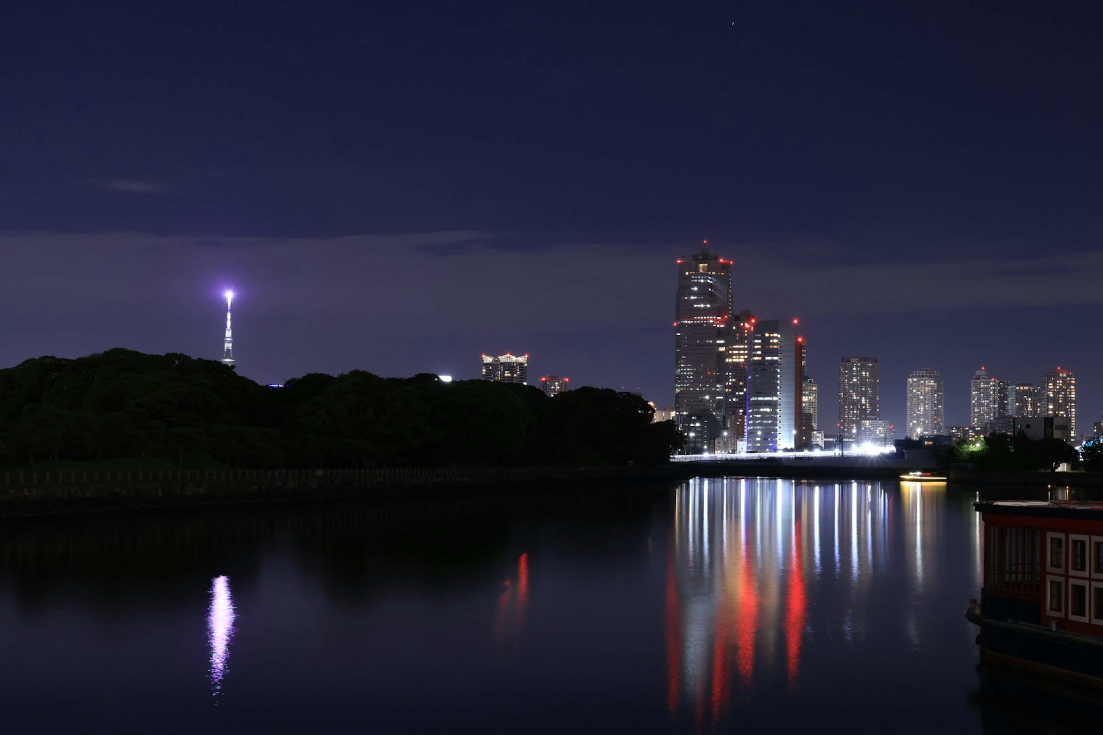 Vista notturna di Tokyo con grattacieli illuminati e riflessi sull'acqua