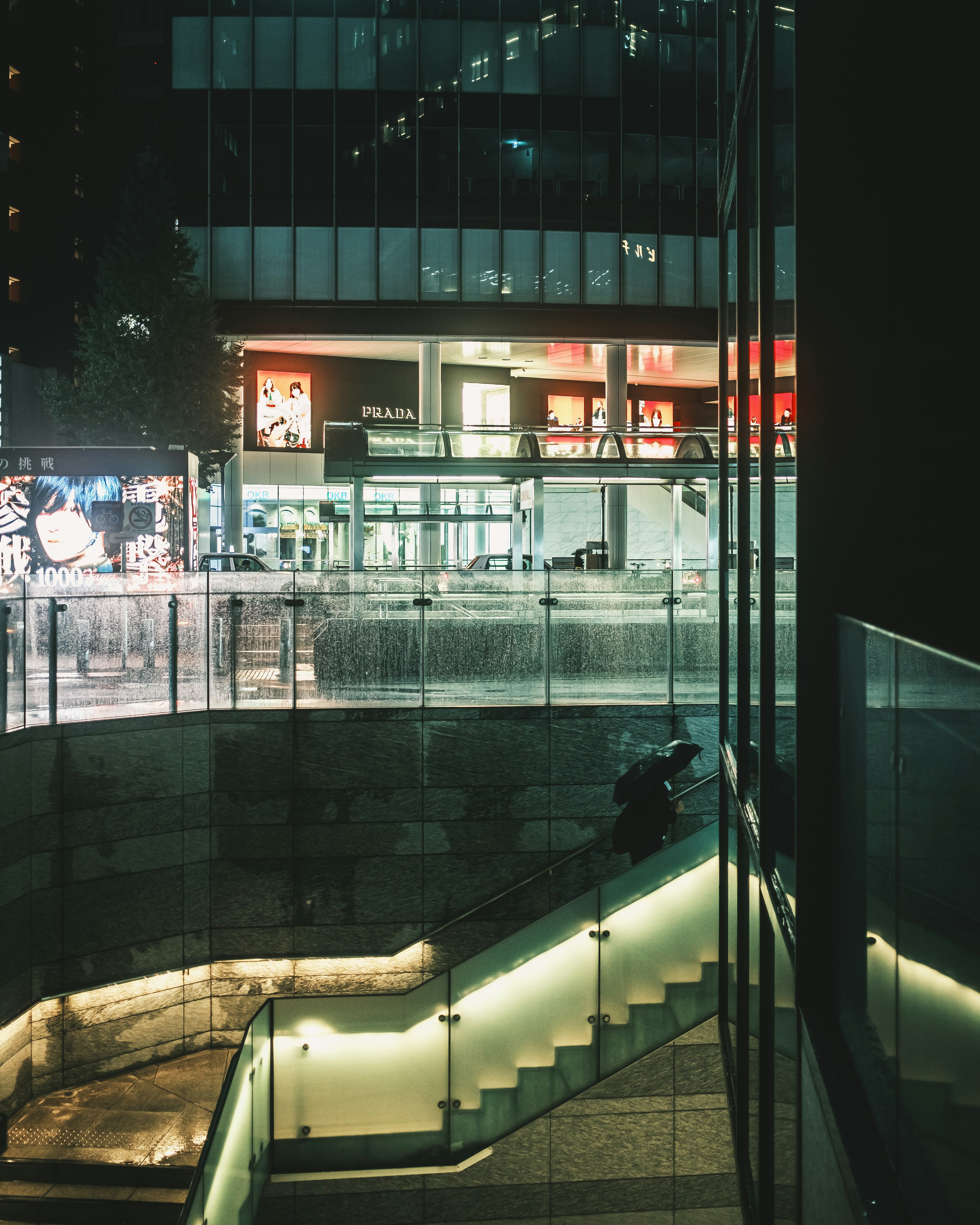 Außenansicht eines Glasgebäudes bei Nacht mit beleuchteten Treppen