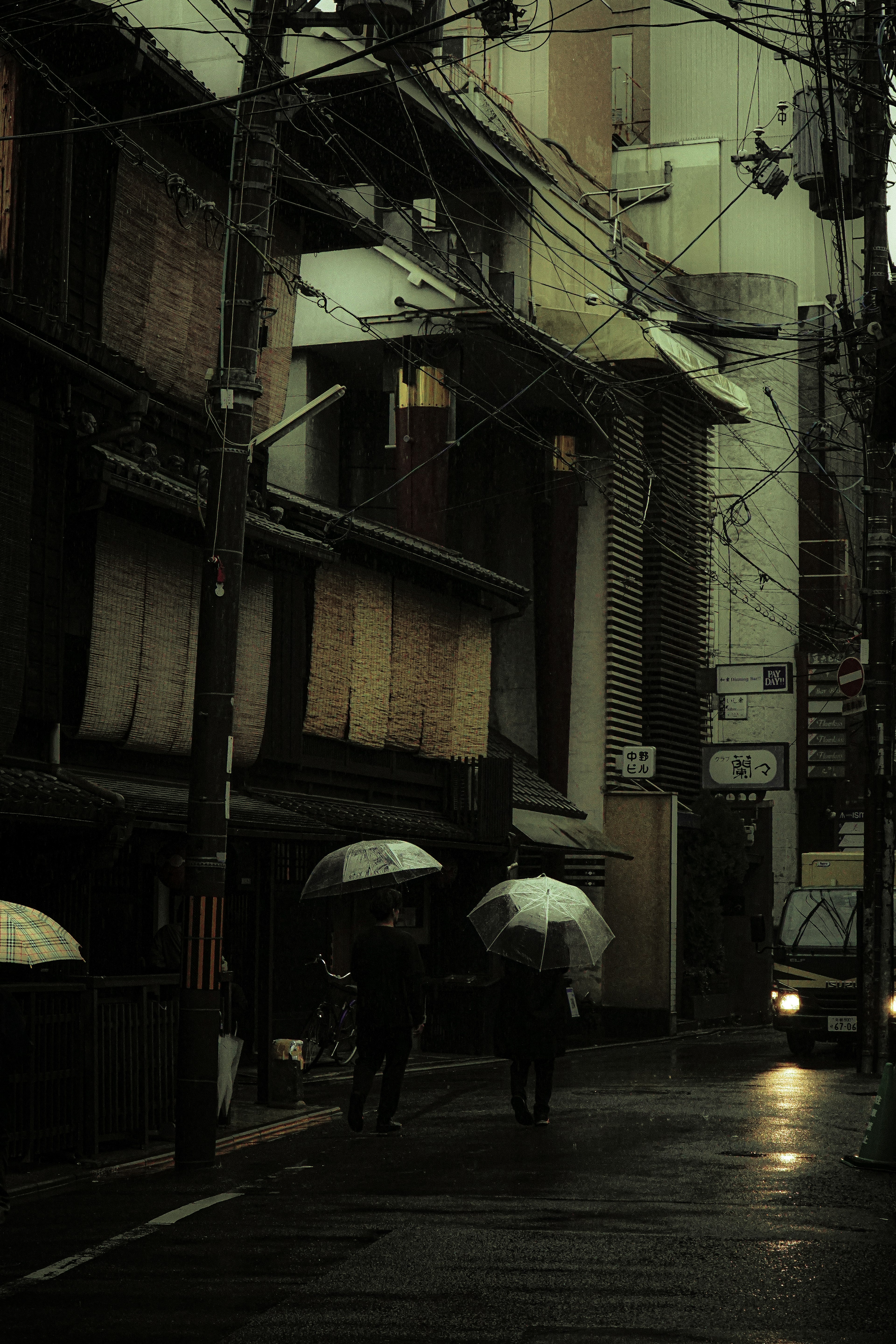 Deux personnes marchant avec des parapluies dans une ruelle sombre