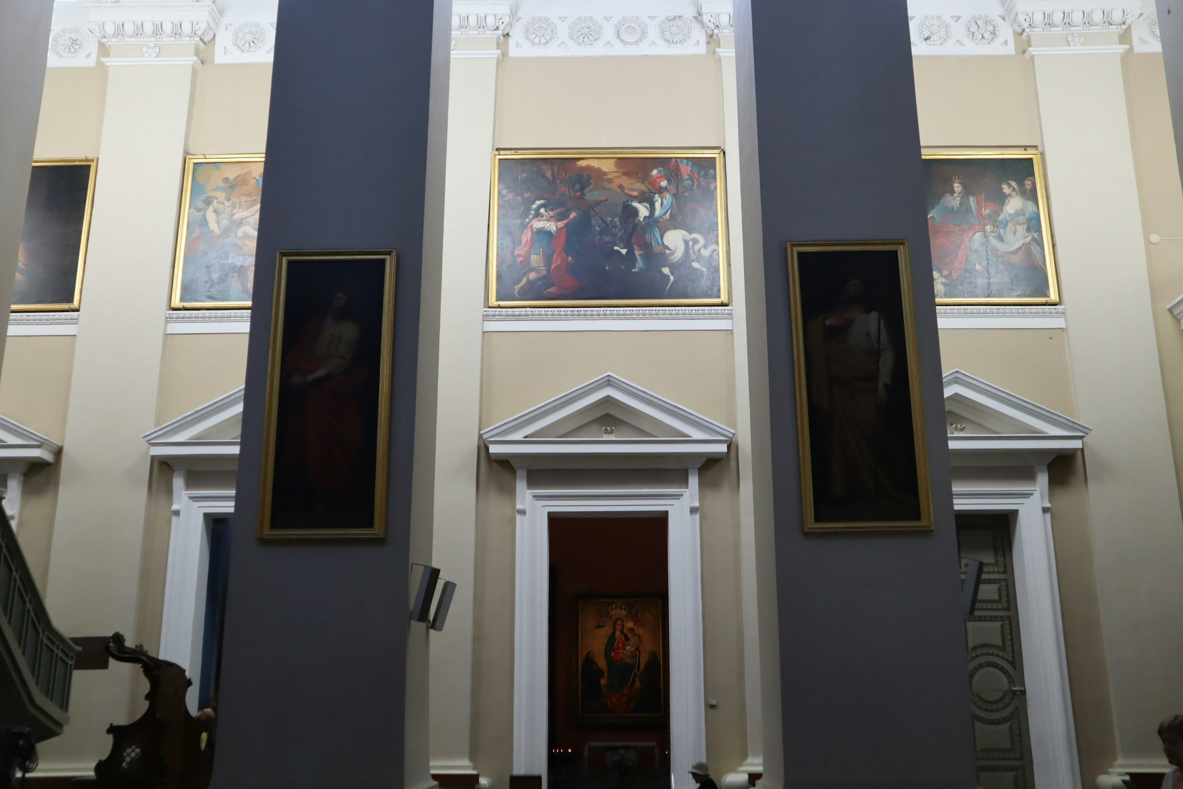 Interior of an art gallery featuring paintings on walls and white columns