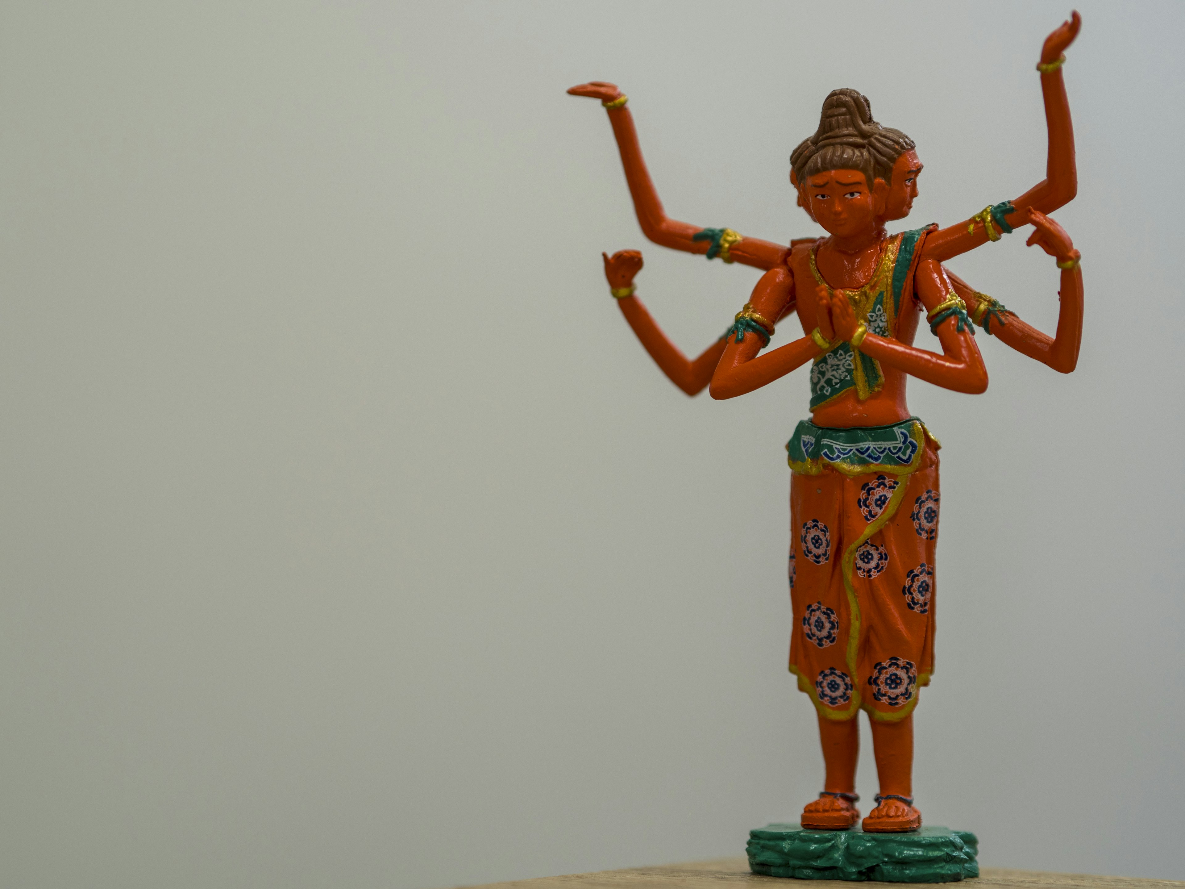 A vibrant orange multi-armed deity statue standing