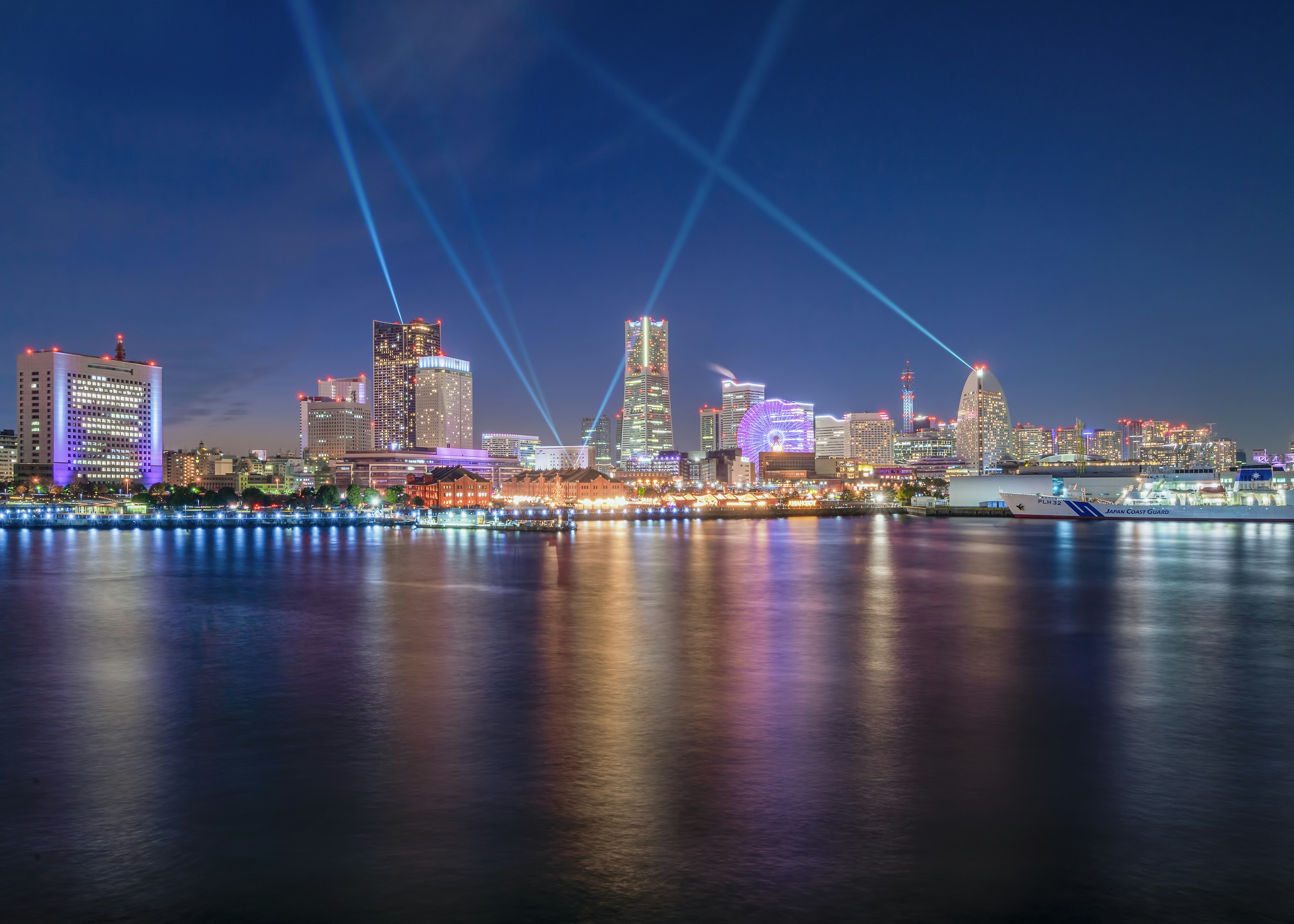 Magnifique paysage urbain nocturne avec des bâtiments lumineux et des faisceaux lumineux se reflétant sur l'eau