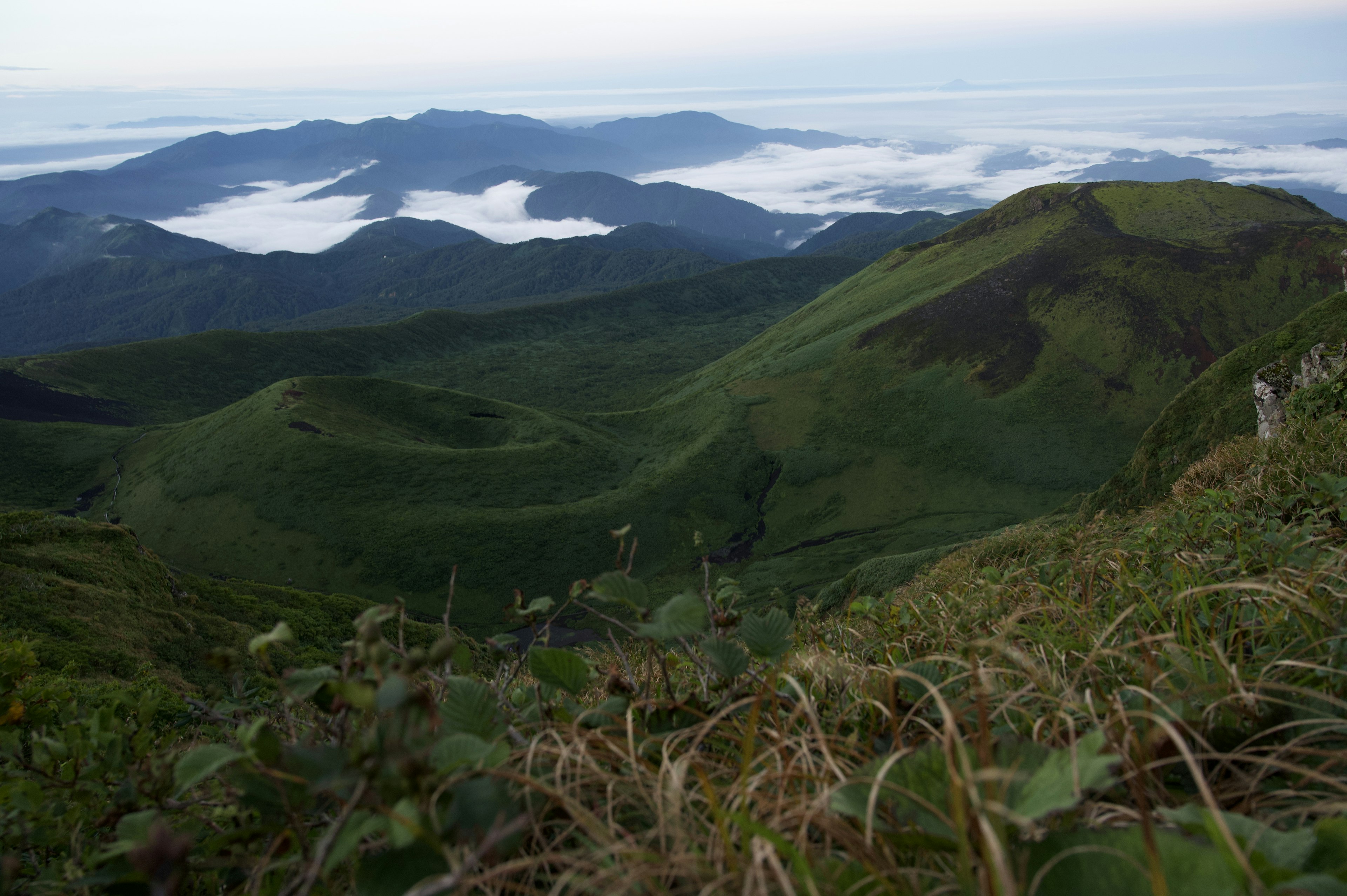 Mountain landscape featuring green hills and a sea of clouds