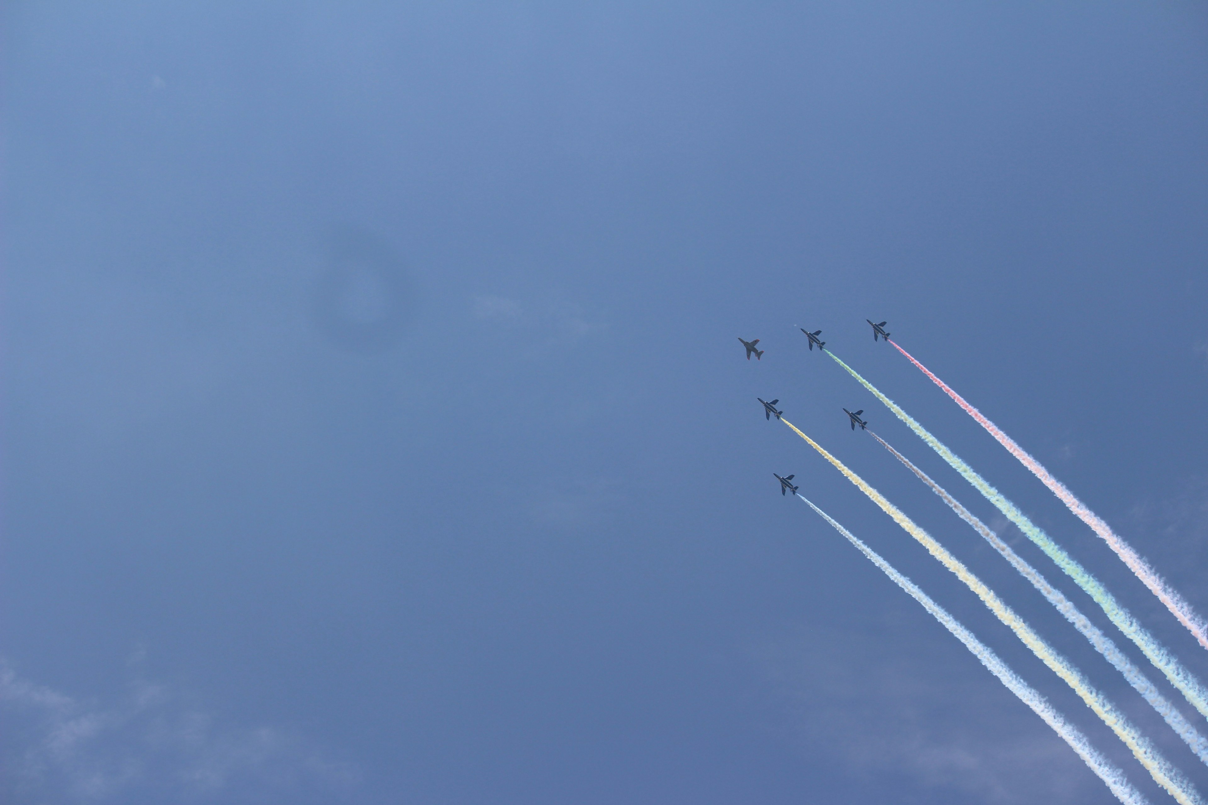 Jet planes flying in the blue sky leaving colorful smoke trails