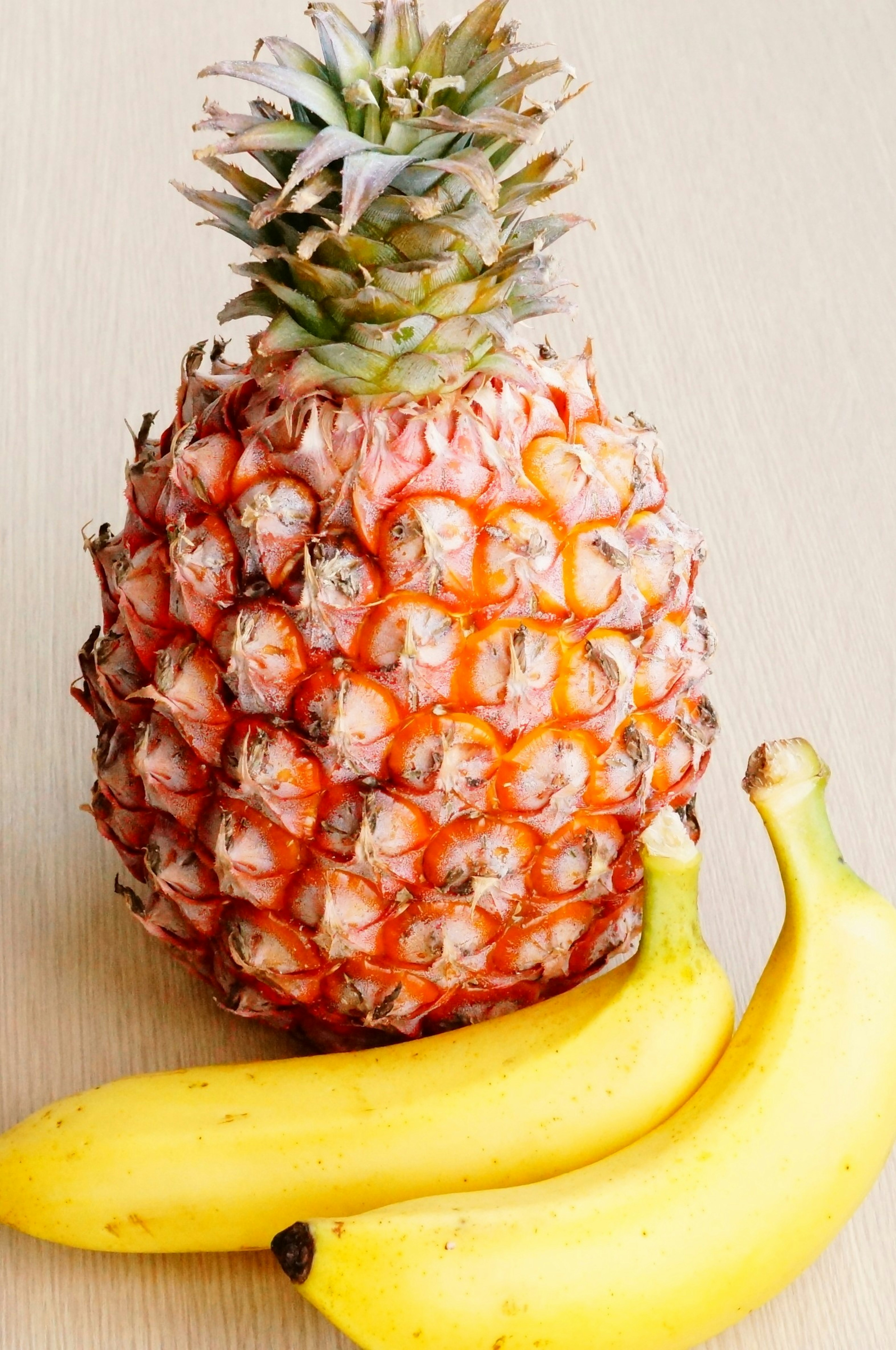 Un ananas et deux bananes sur une surface en bois