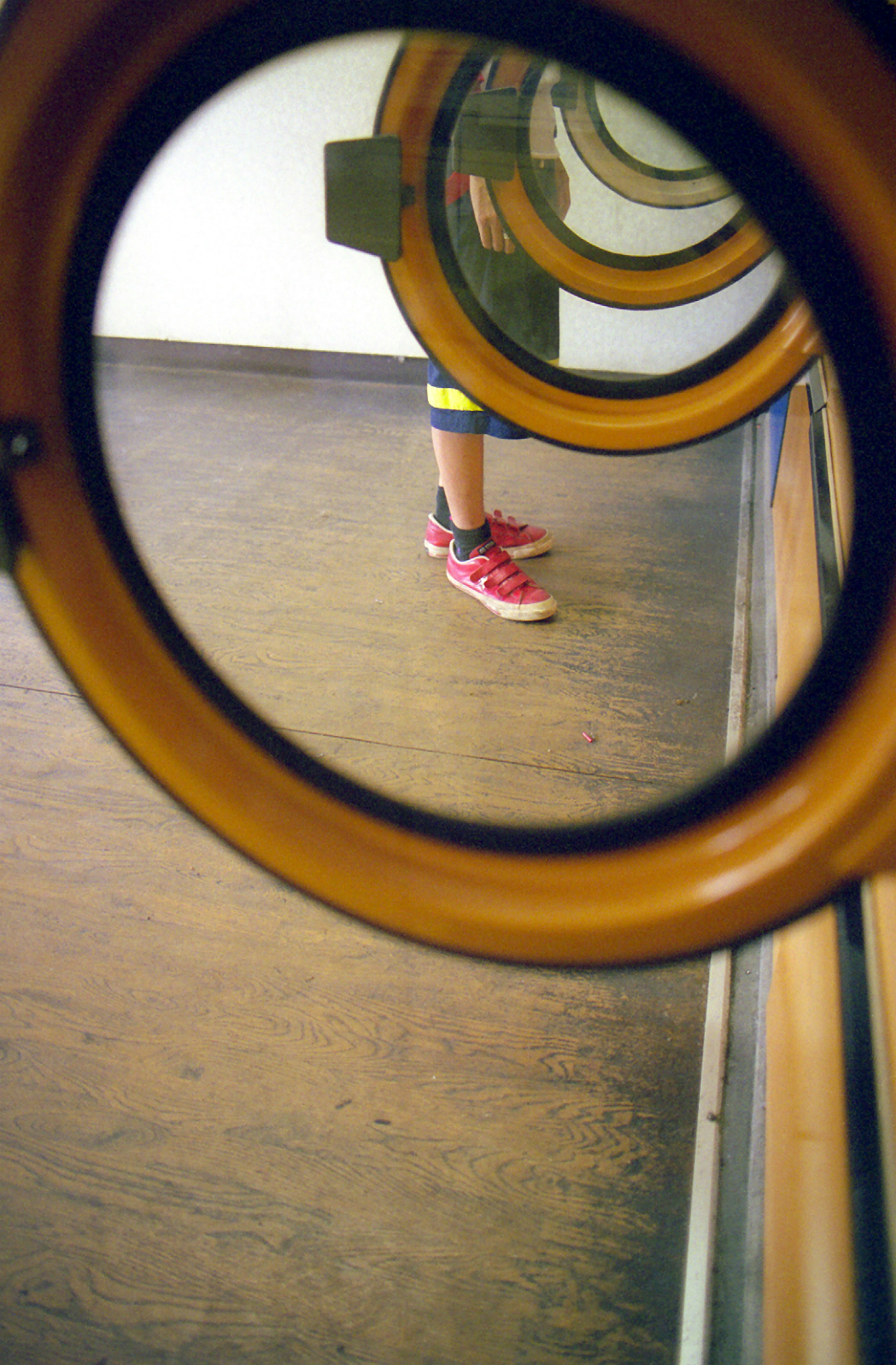 Foot wearing red shoes seen through circular windows and wooden floor