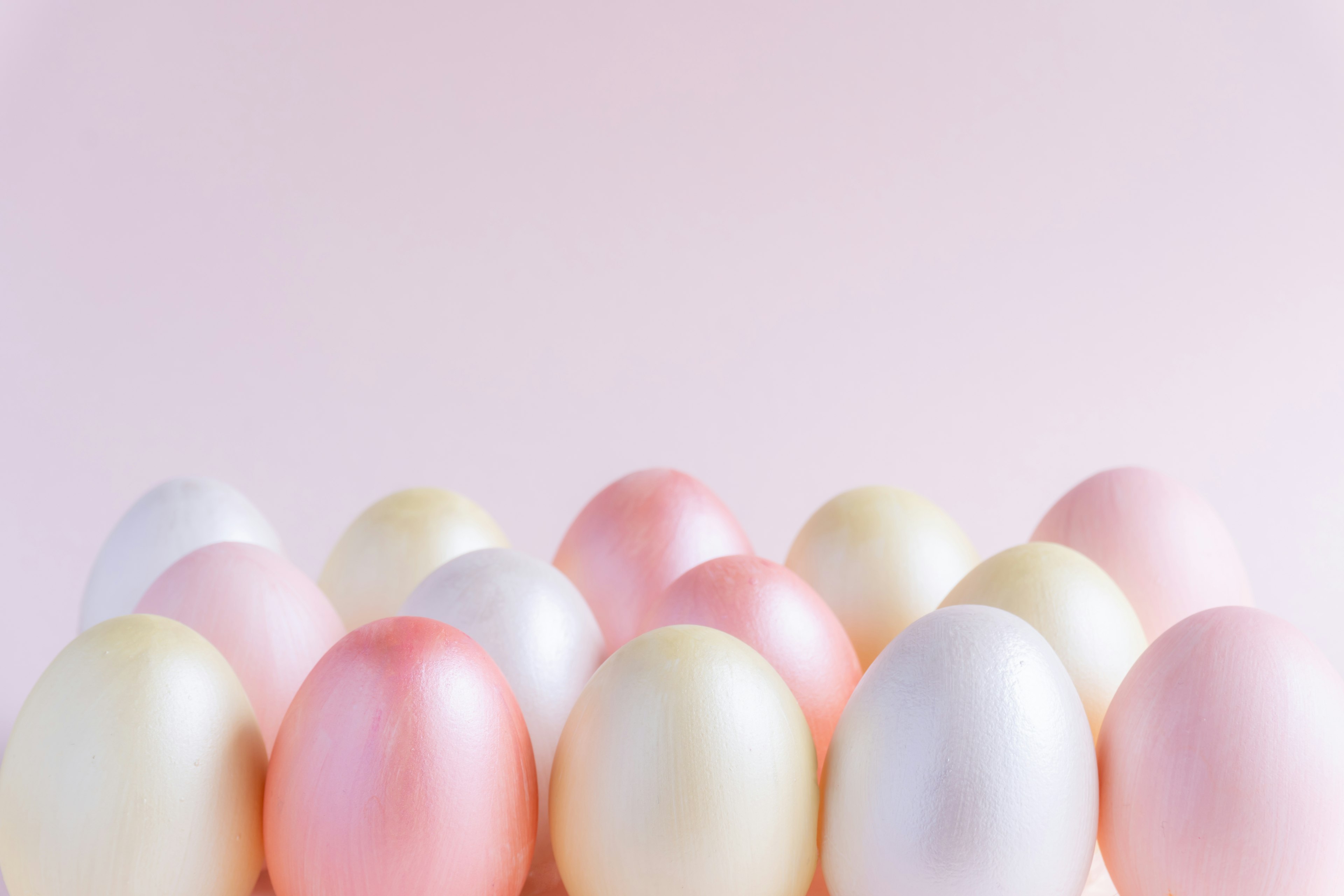 Pastellfarbene Eier auf einem rosa Hintergrund angeordnet