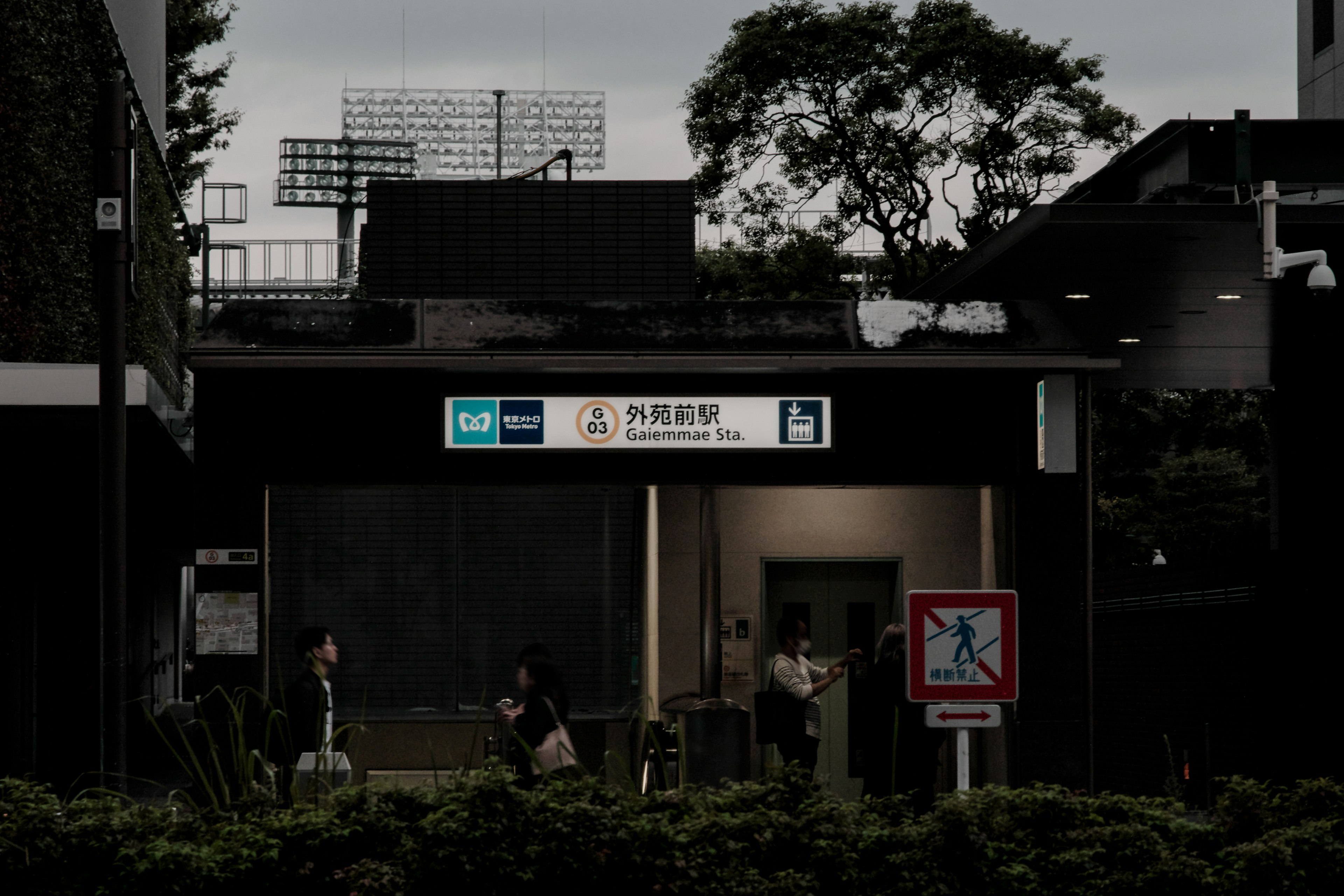 People standing in front of a dimly lit station with signs visible