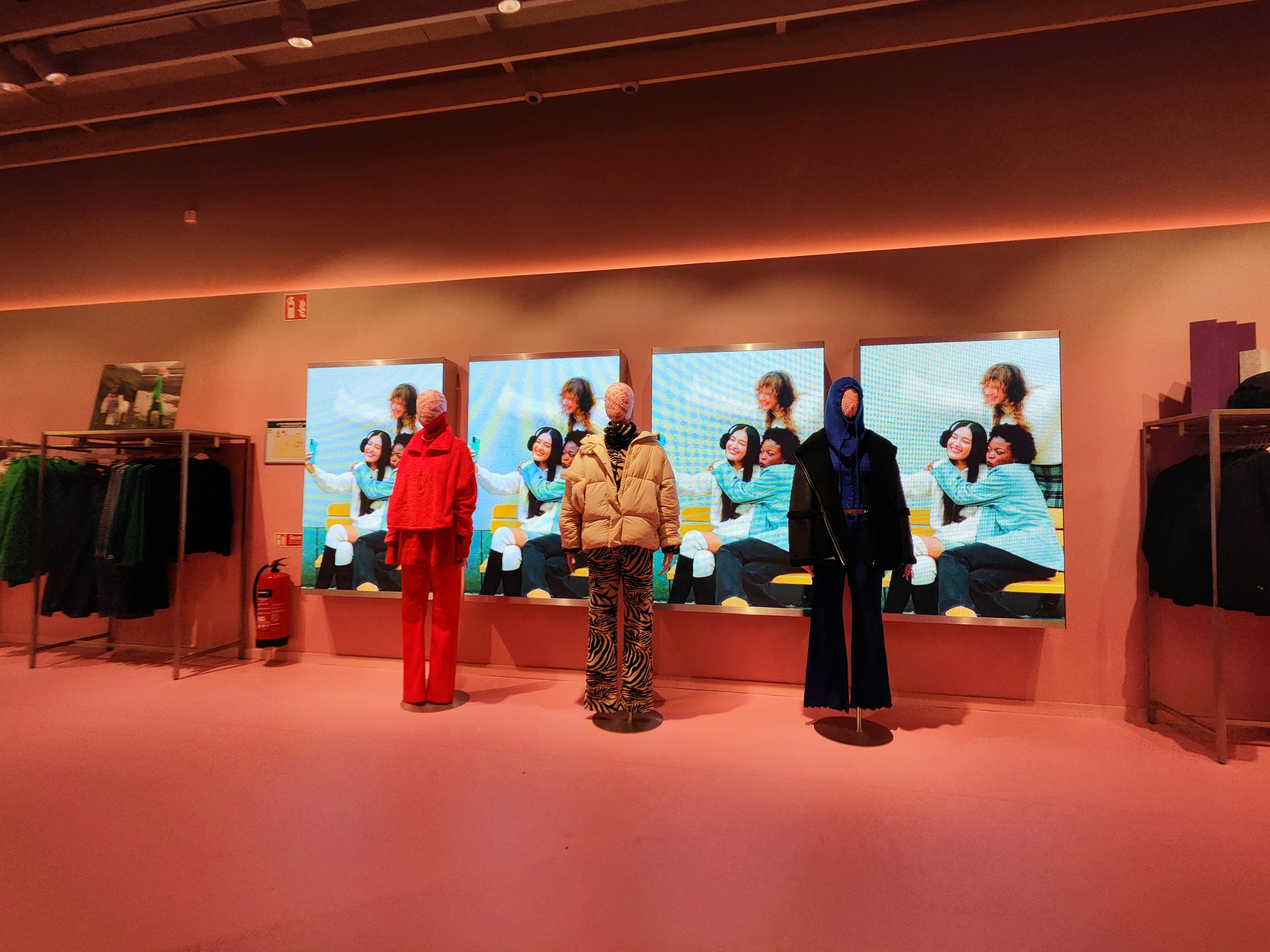 Fashion showroom displaying clothing with digital screens featuring models