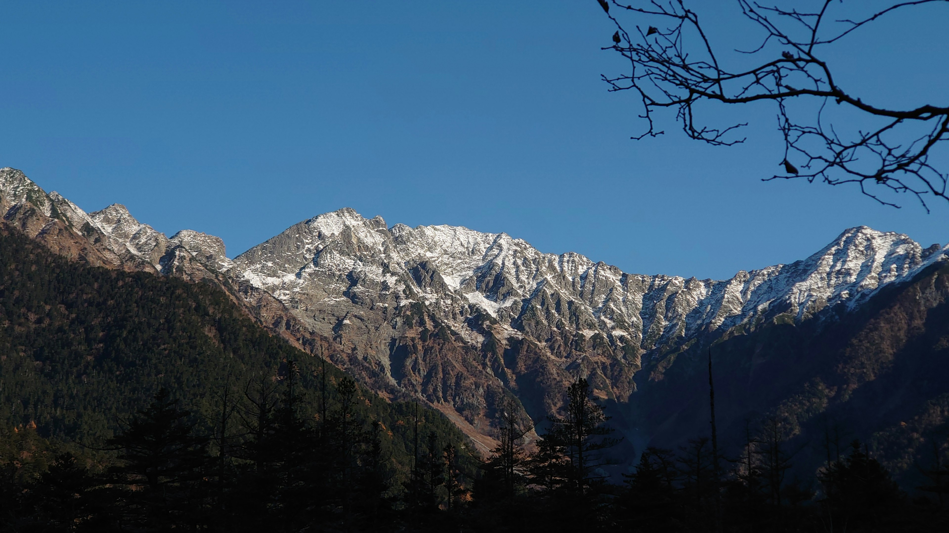 青空の下に雪をかぶった山々が広がる風景