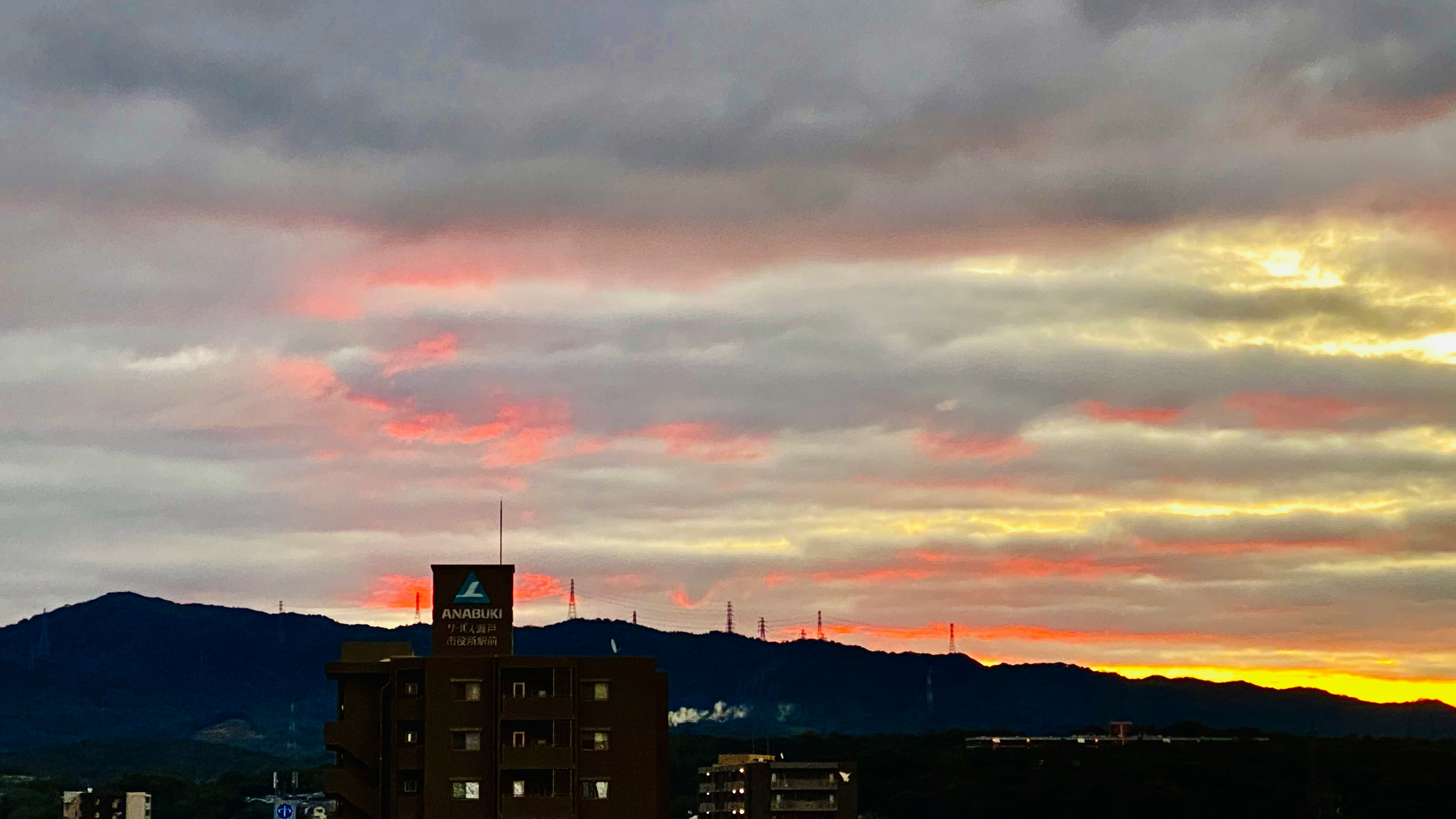 夕焼けの空に浮かぶ雲と山のシルエット